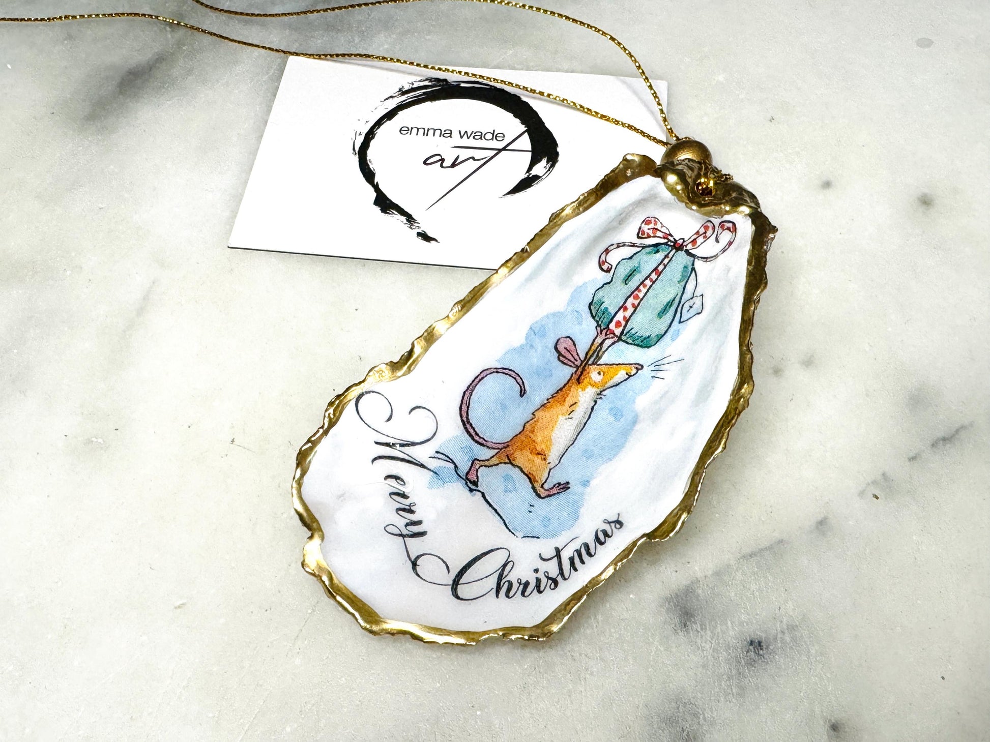 Handmade Dorset oyster shell Christmas ornament featuring a whimsical festive mouse illustration with gold leaf edging, glossy resin finish, and hanging ribbon. Coastal Christmas decoration styled as a luxury handmade oyster shell bauble and festive trinket keepsake gift.
