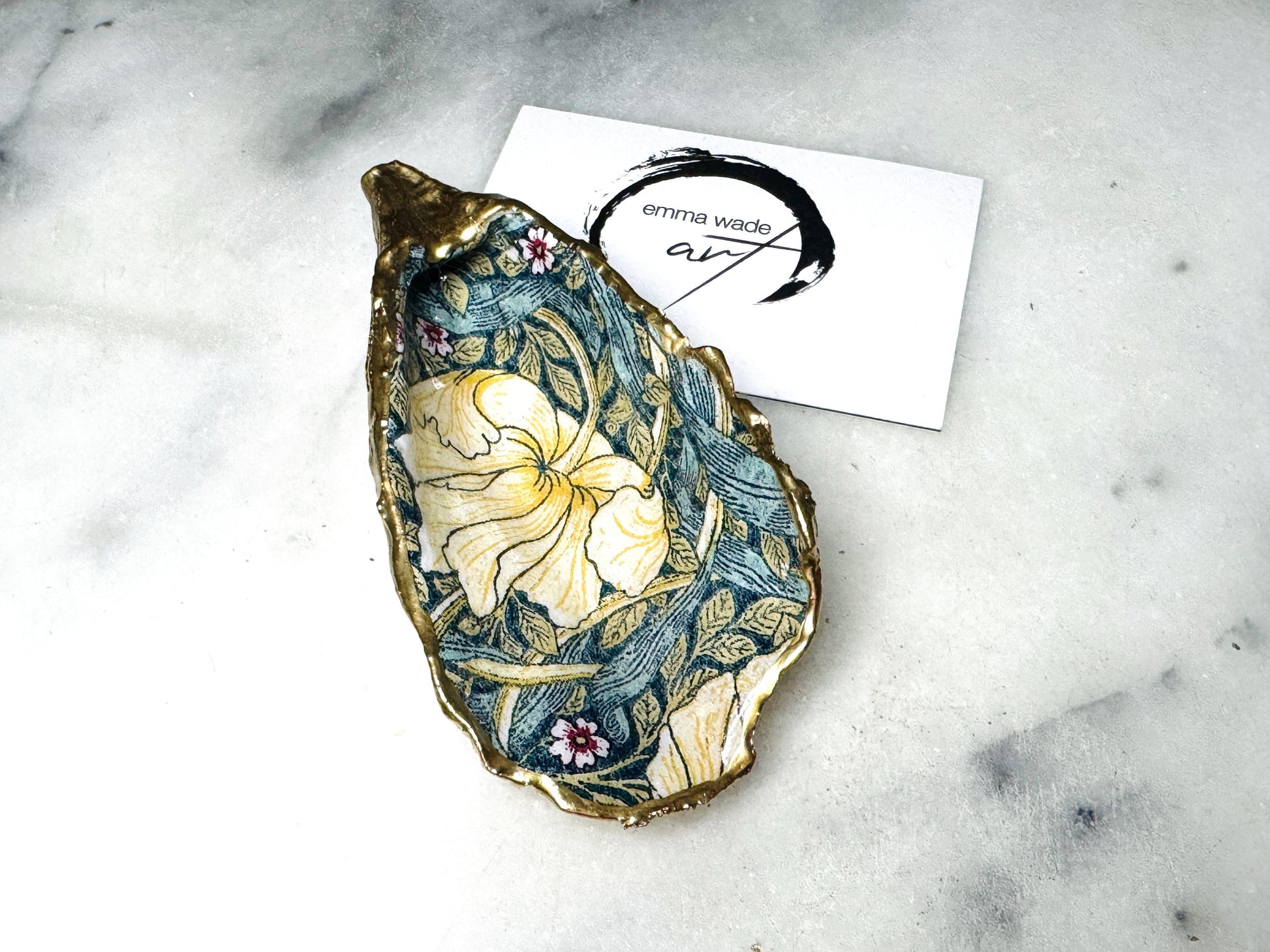 William Morris Golden Green Pimpernel oyster shell ring dish with gold leaf edge. A unique shell ring holder, ring tray, and jewellery organiser for rings, earrings, or cufflinks. Each shell features an art inspired floral design and is individually handmade from Dorset shells. Perfect as a trinket dish for bedside or dressing table storage. A thoughtful gift for weddings, anniversaries, birthdays, bridesmaids, or Christmas. A sustainable decorative keepsake for any jewellery lover.