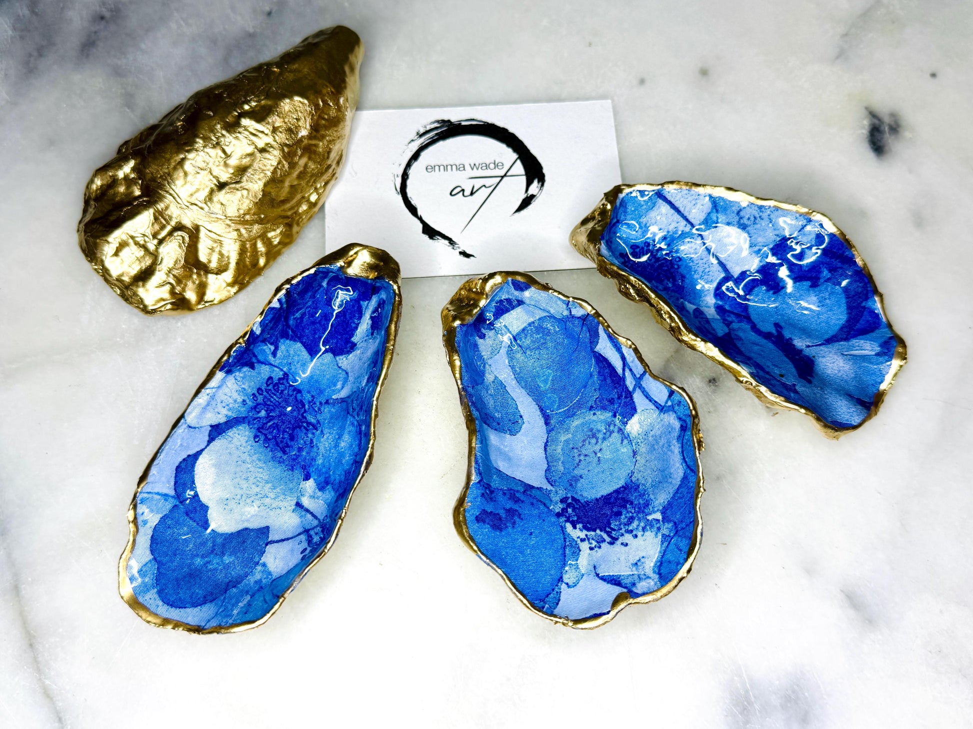 Pair of oyster shell salt and pepper dishes with deep blue watercolour flower design, finished with gold leaf trim and glossy seal. Handmade from Dorset oyster shells, each dish is unique with natural variations. A beautiful oyster shell salt gift set, also available with matching gold crystal spoons for a finishing touch. Perfect for weddings, anniversaries, dinner parties, or as a handmade gift for birthdays, Christmas, or housewarmings. Elegant coastal tableware and decor piece.