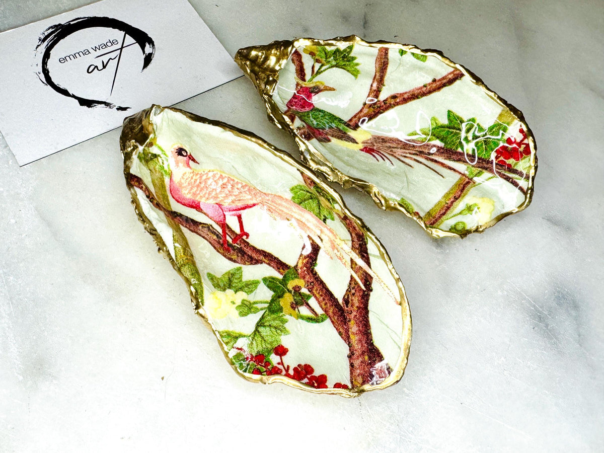 Handmade oyster shell trinket dish featuring colourful Bird of Paradise artwork with gold leaf edging and glossy resin finish. Tropical coastal jewellery dish crafted from natural Dorset shells, styled as a ring holder, keepsake tray, or exotic nature-inspired gift.