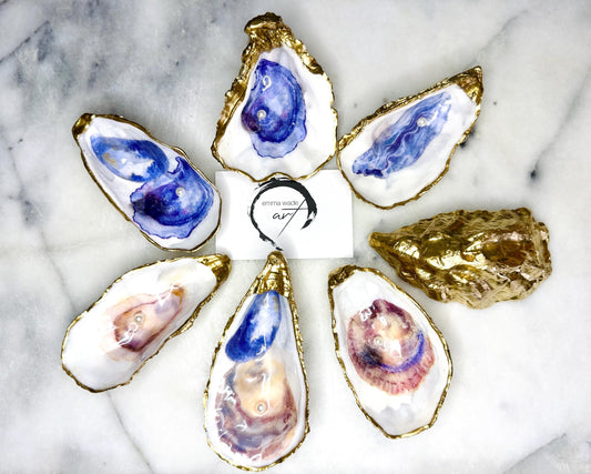 Handmade Dorset oyster shell jewellery dish with a natural pearl finish, gilded with liquid gold leaf and sealed in glossy resin. Each oyster shell features a Swarovski pearl inside, making it a unique ring holder, trinket tray, or coastal-inspired jewellery organiser. Perfect as a handmade oyster ring dish for weddings, anniversaries, birthdays, or as a bridesmaid gift. A one-of-a-kind shell catchall tray, ideal for coastal home décor or thoughtful handmade presents.