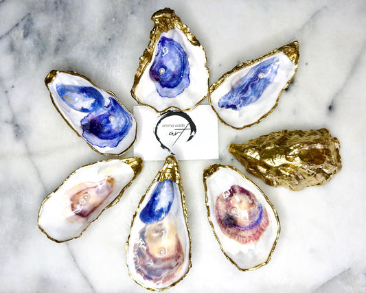Handmade Dorset oyster shell jewellery dish with a natural pearl finish, gilded with liquid gold leaf and sealed in glossy resin. Each oyster shell features a Swarovski pearl inside, making it a unique ring holder, trinket tray, or coastal-inspired jewellery organiser. Perfect as a handmade oyster ring dish for weddings, anniversaries, birthdays, or as a bridesmaid gift. A one-of-a-kind shell catchall tray, ideal for coastal home décor or thoughtful handmade presents.