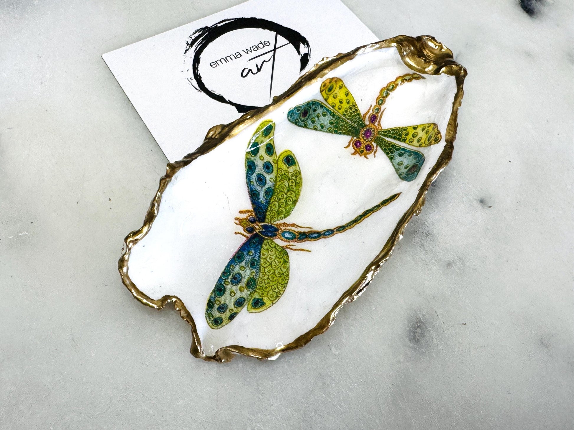 Handmade dragonfly oyster shell trinket dish with hand-gilded gold leaf edges and glossy resin finish, created from sustainably sourced Dorset shells. Unique coastal jewellery holder and ring dish, ideal as a vanity tray, trinket tray or decorative keepsake. Nature inspired home decor gift for birthdays, weddings, anniversaries, housewarmings and Mother’s Day. One of a kind artisan shell dish, beautifully presented in a gift box.