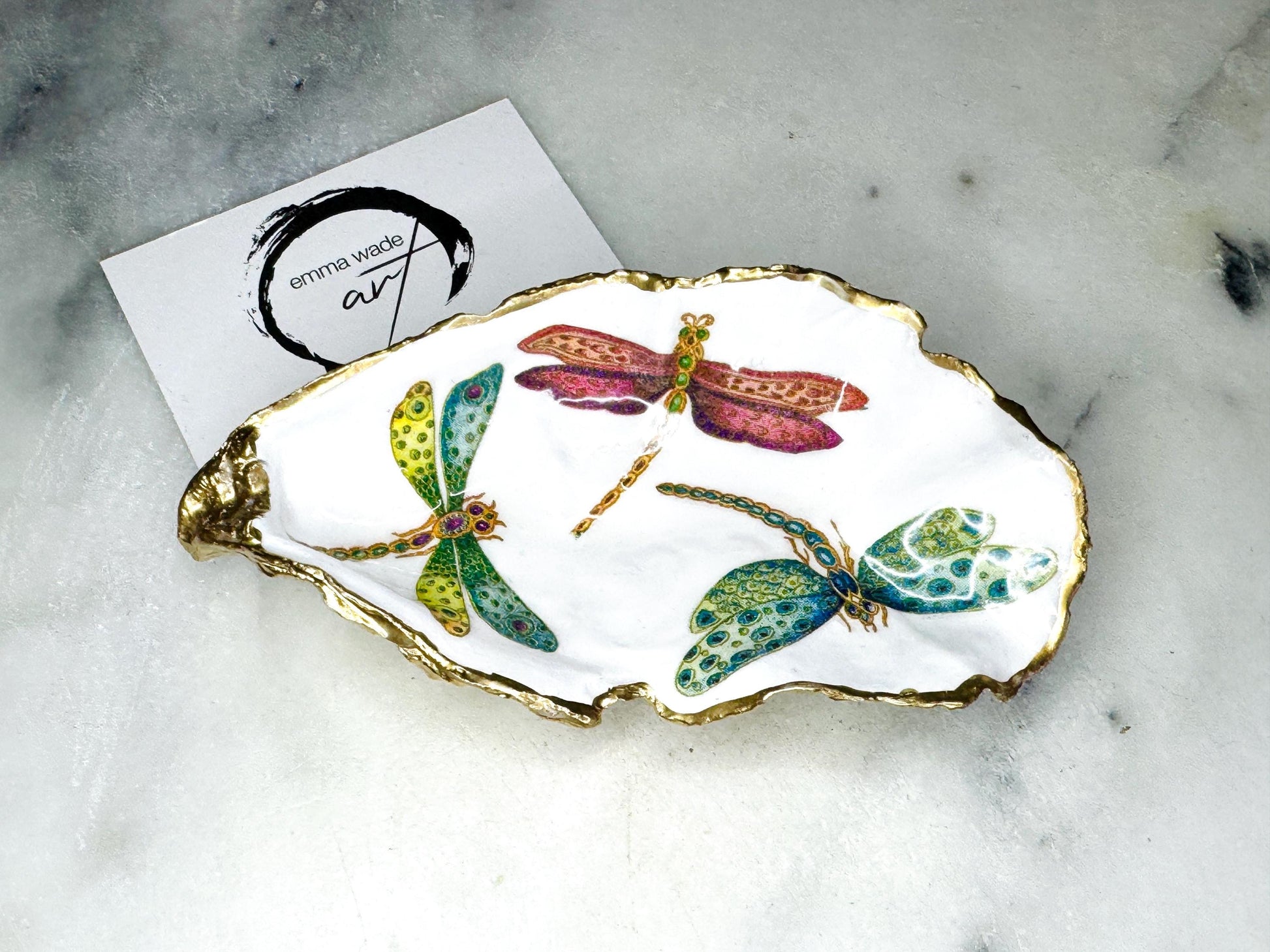 Handmade dragonfly oyster shell trinket dish with hand-gilded gold leaf edges and glossy resin finish, created from sustainably sourced Dorset shells. Unique coastal jewellery holder and ring dish, ideal as a vanity tray, trinket tray or decorative keepsake. Nature inspired home decor gift for birthdays, weddings, anniversaries, housewarmings and Mother’s Day. One of a kind artisan shell dish, beautifully presented in a gift box.