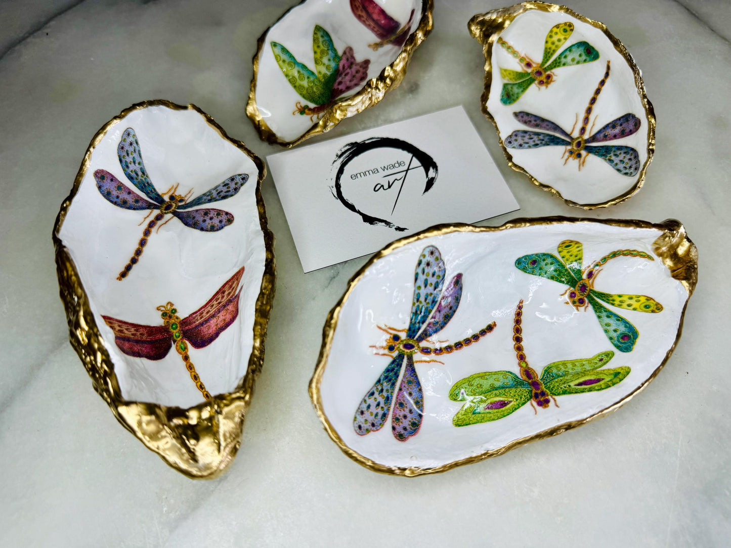 Handmade dragonfly oyster shell trinket dish with hand-gilded gold leaf edges and glossy resin finish, created from sustainably sourced Dorset shells. Unique coastal jewellery holder and ring dish, ideal as a vanity tray, trinket tray or decorative keepsake. Nature inspired home decor gift for birthdays, weddings, anniversaries, housewarmings and Mother’s Day. One of a kind artisan shell dish, beautifully presented in a gift box.