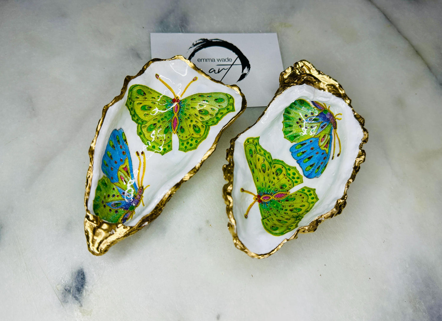 Handmade butterfly oyster shell trinket dish with colourful blue green and pink butterfly designs, edged and backed in gold leaf, Dorset coastal shell jewellery holder with glossy resin finish, luxury ring dish, coastal home decor gift, unique handmade shell dish for jewellery storage, beach house accessory, UK artisan oyster shell dish