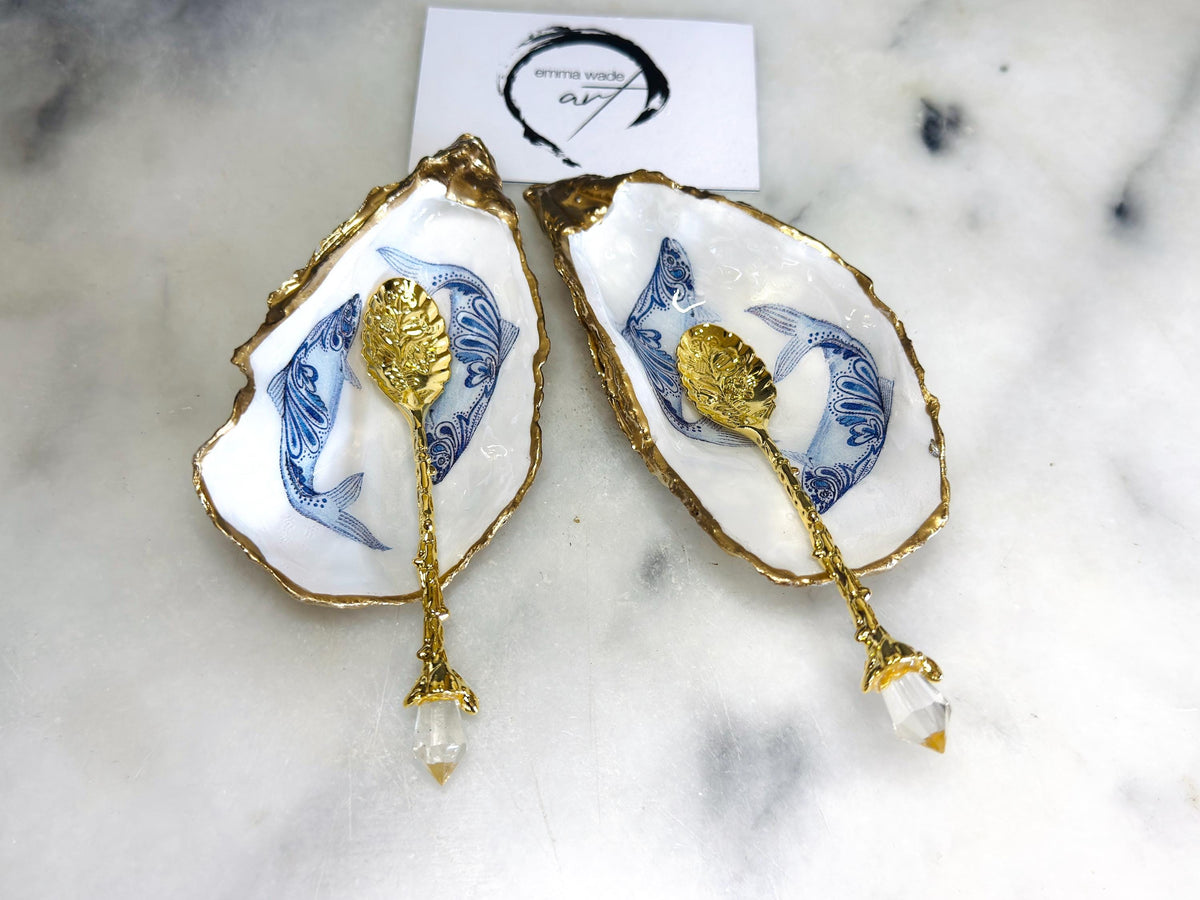 Handmade Dorset oyster shell salt and pepper pinch pots featuring blue paisley fish designs with gold leaf edging and glossy resin finish. Coastal oyster shell cruet set with natural pearlescent interiors and optional gold spoons, styled as elegant nautical table décor and condiment dishes.