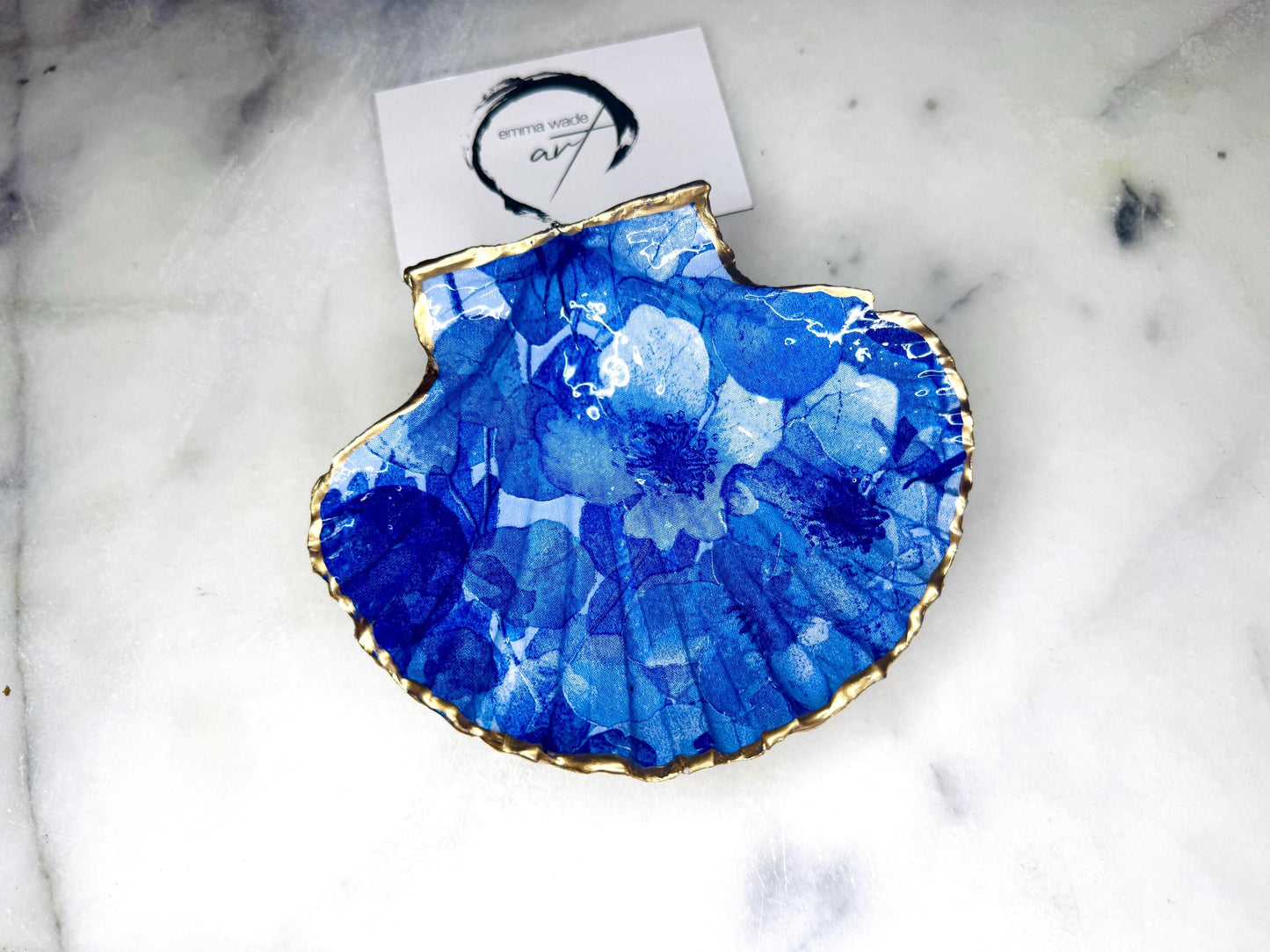 Deep blue watercolour floral scallop shell trinket dish with hand gilded gold leaf edging and glossy resin finish. Handmade Dorset shell jewellery holder in rich cobalt and ocean blue tones, styled as coastal home décor with pearls and gold details.