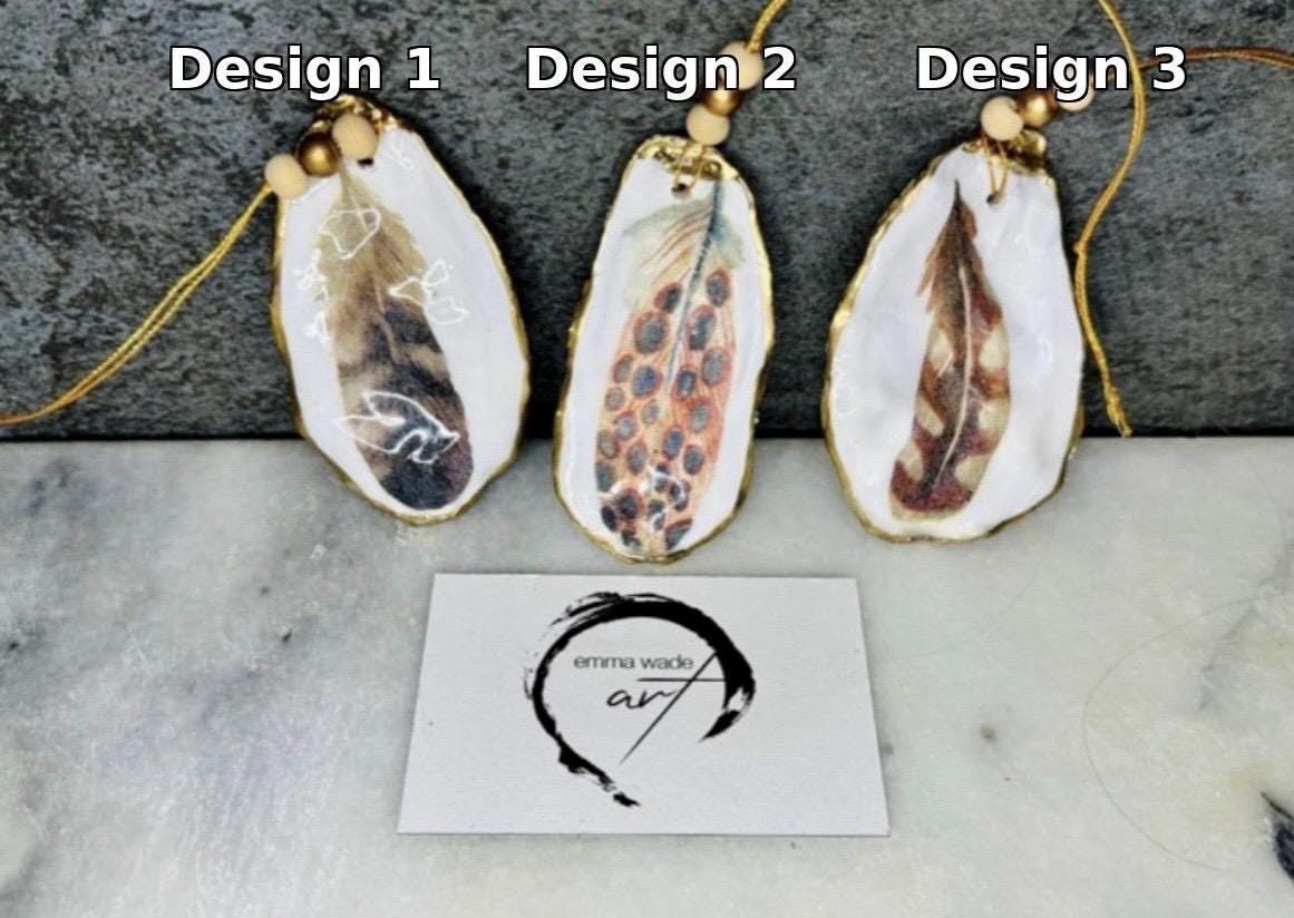 Aquarelle feather oyster shell hanging ornaments, handmade coastal décor, gilded gold leaf shells, resin sealed feather decorations, Christmas tree ornaments, nature-inspired gifts, watercolor feather oyster shells, Dorset handmade shell ornaments, sustainable coastal gifts, oyster shell art, feather design decorations, unique shell ornaments, eco-friendly handmade oyster shell Christmas gifts.
