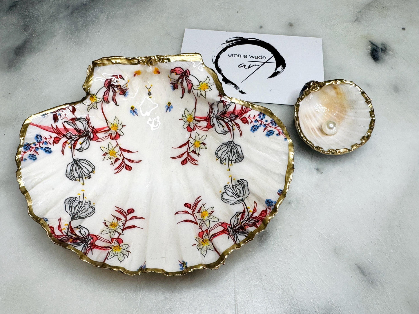 Handcrafted Dorset shell dish set featuring red and blue floral designs on scallop and cockle shells | Cockle shell includes a Swarovski pearl ring rest to prevent rings from sliding | Gilded with liquid gold leaf and sealed with glossy resin | Perfect as a jewellery or ring holder, trinket tray, or coastal gift | Each shell is sustainably sourced and hand finished in the UK | Ideal wedding or anniversary keepsake