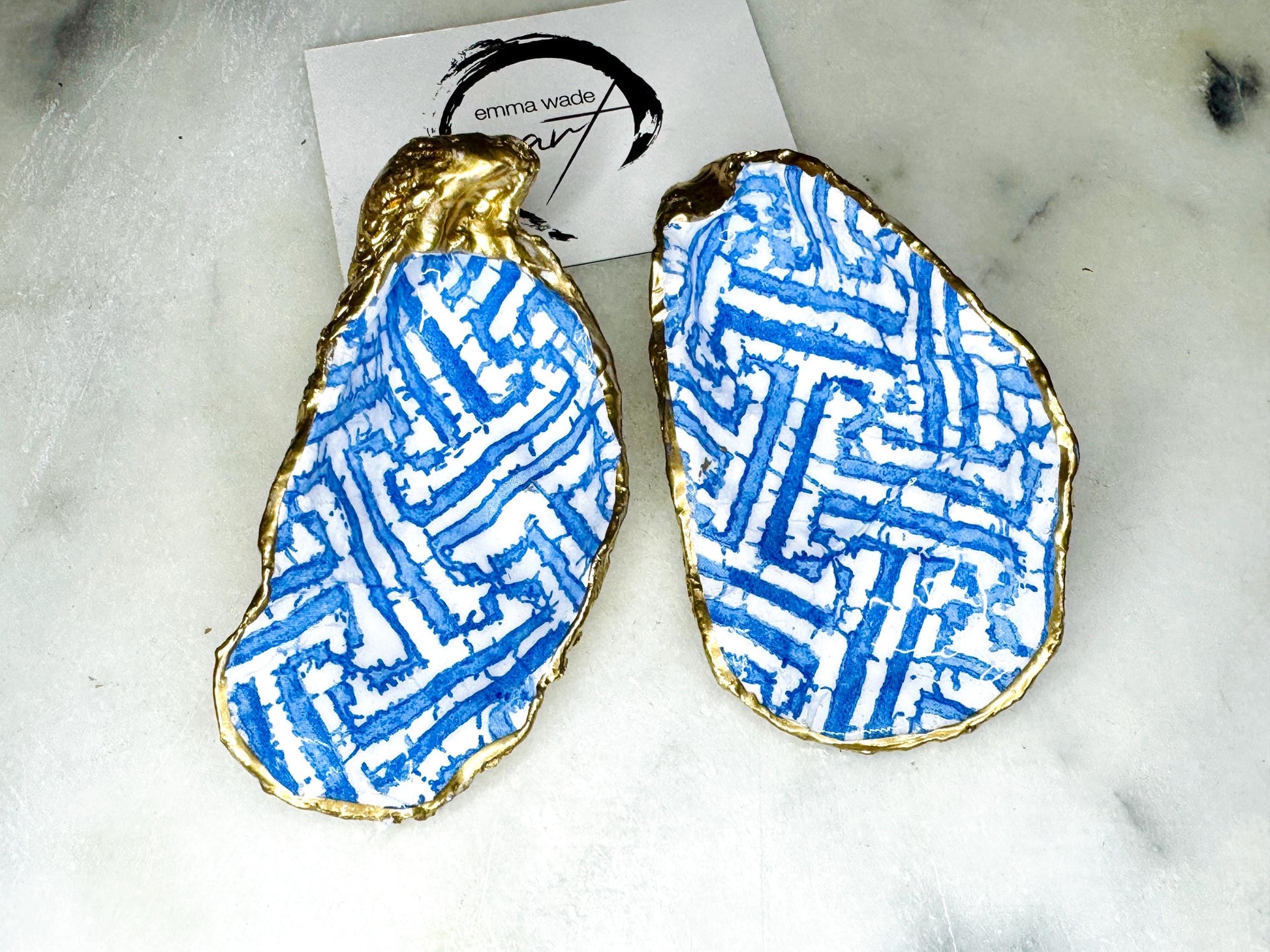 Handmade blue fretwork oyster shell trinket dish shown as a single piece, crafted from a natural Dorset oyster shell and finished with genuine gold leaf edges and glossy resin. Featuring an intricate blue fretwork pattern, this jewellery and ring holder is perfect for a bedside table, bathroom or coastal-inspired decor. Each shell is one of a kind and carefully finished by hand.