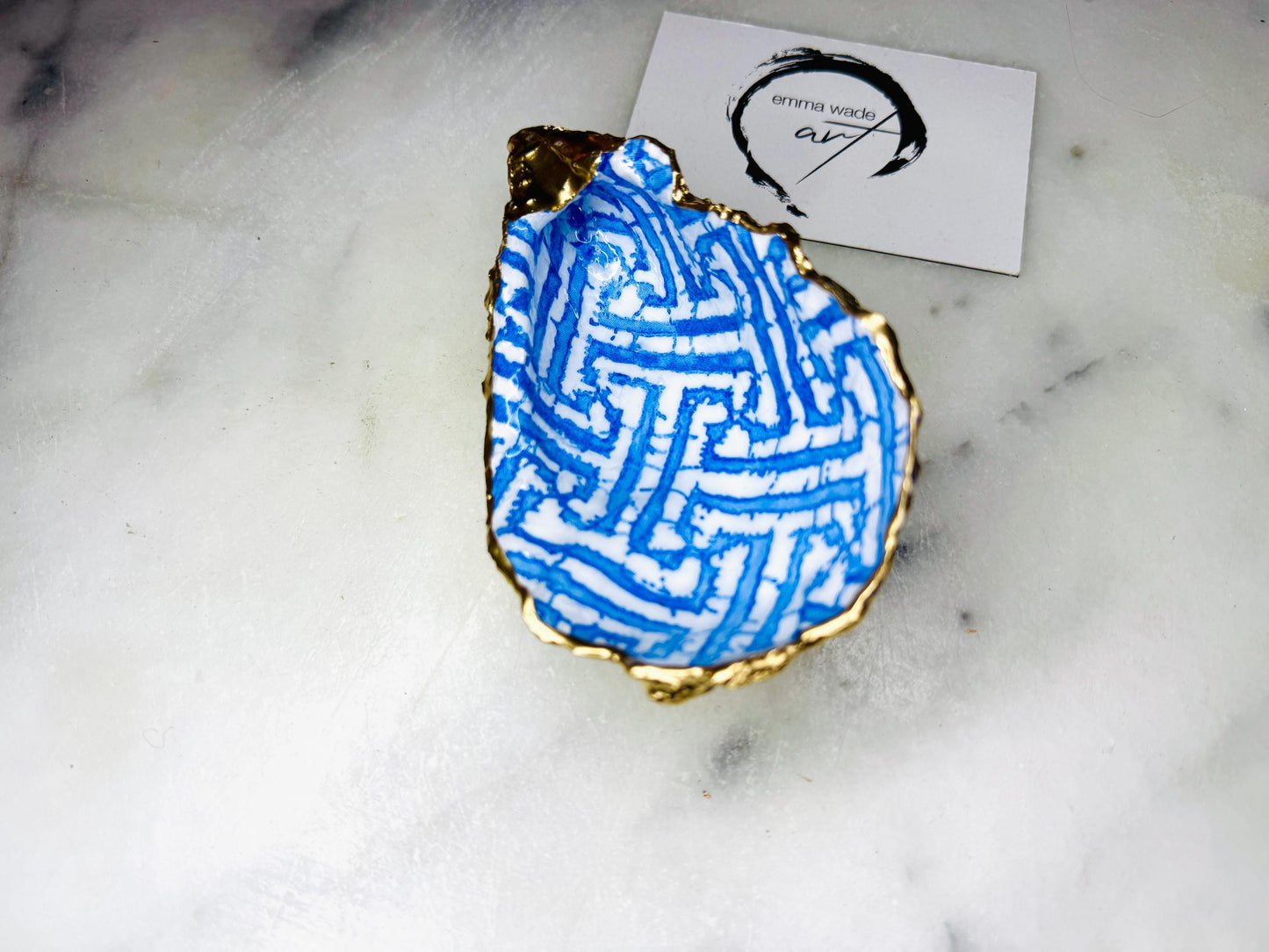 Handmade blue fretwork oyster shell trinket dish shown as a single piece, crafted from a natural Dorset oyster shell and finished with genuine gold leaf edges and glossy resin. Featuring an intricate blue fretwork pattern, this jewellery and ring holder is perfect for a bedside table, bathroom or coastal-inspired decor. Each shell is one of a kind and carefully finished by hand.