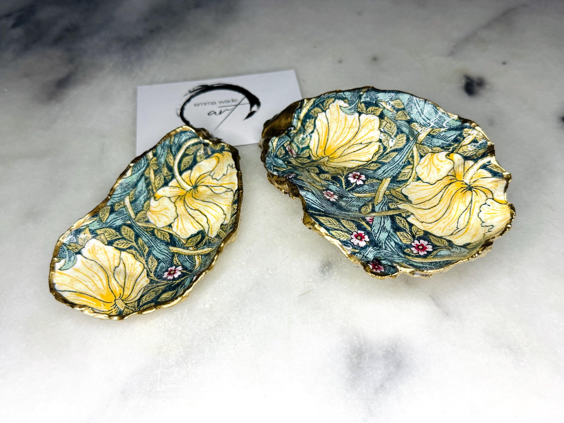 William Morris Golden Green Pimpernel oyster shell ring dish with gold leaf edge. A unique shell ring holder, ring tray, and jewellery organiser for rings, earrings, or cufflinks. Each shell features an art inspired floral design and is individually handmade from Dorset shells. Perfect as a trinket dish for bedside or dressing table storage. A thoughtful gift for weddings, anniversaries, birthdays, bridesmaids, or Christmas. A sustainable decorative keepsake for any jewellery lover.