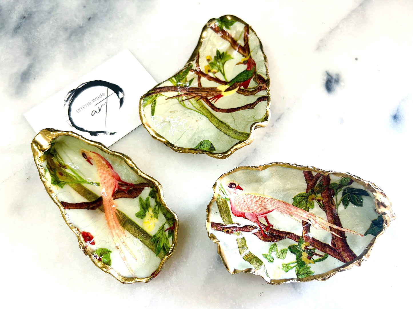 Handmade oyster shell trinket dish featuring colourful Bird of Paradise artwork with gold leaf edging and glossy resin finish. Tropical coastal jewellery dish crafted from natural Dorset shells, styled as a ring holder, keepsake tray, or exotic nature-inspired gift.