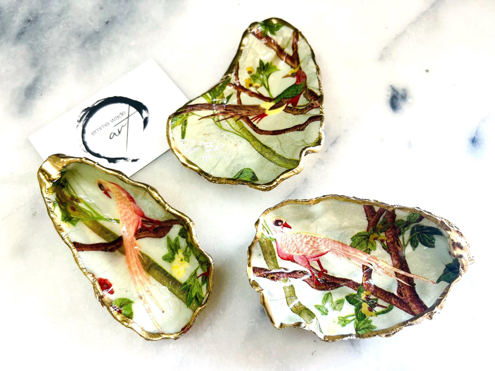 Handmade oyster shell trinket dish featuring colourful Bird of Paradise artwork with gold leaf edging and glossy resin finish. Tropical coastal jewellery dish crafted from natural Dorset shells, styled as a ring holder, keepsake tray, or exotic nature-inspired gift.