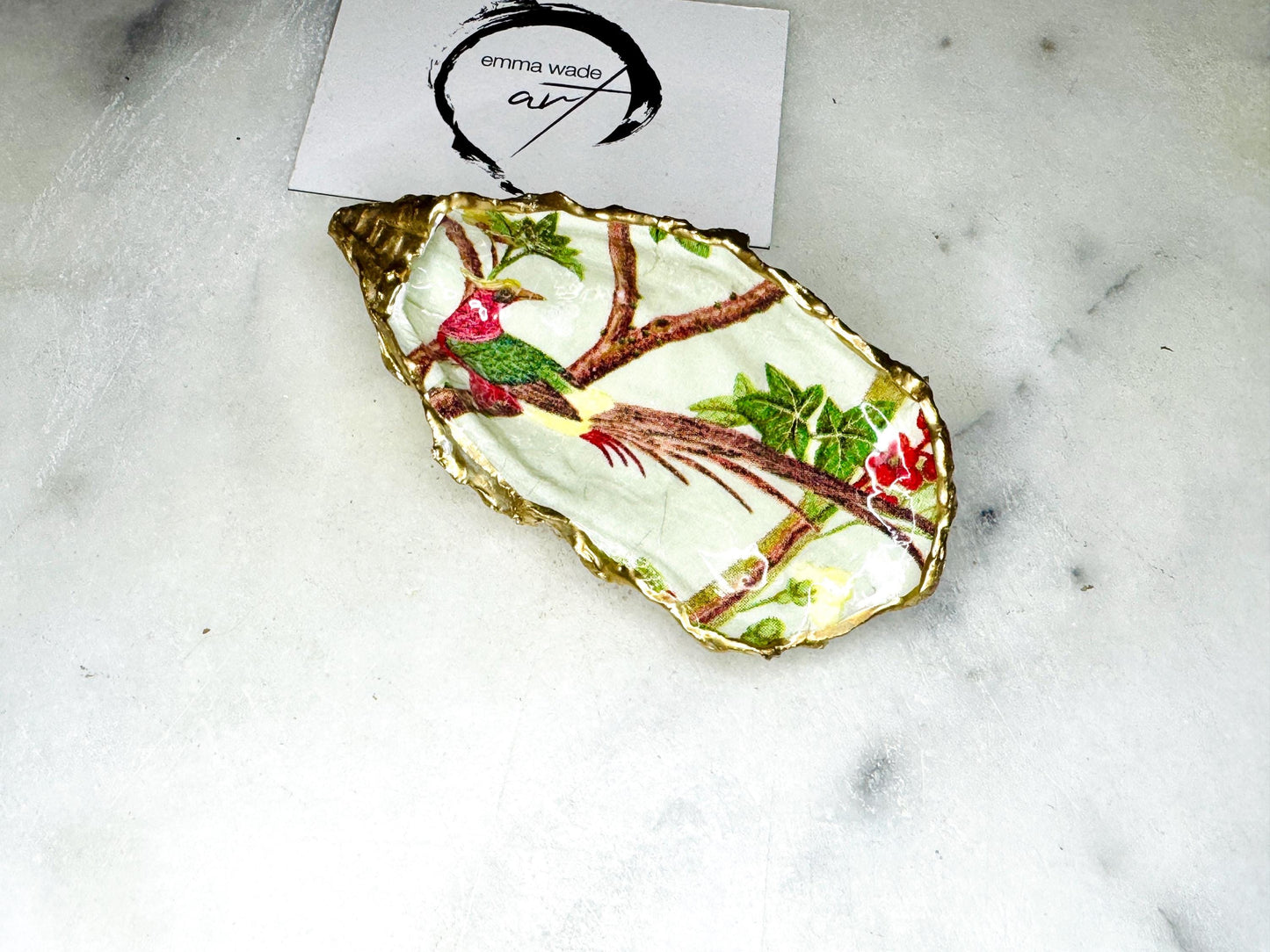 Handmade oyster shell trinket dish featuring colourful Bird of Paradise artwork with gold leaf edging and glossy resin finish. Tropical coastal jewellery dish crafted from natural Dorset shells, styled as a ring holder, keepsake tray, or exotic nature-inspired gift.