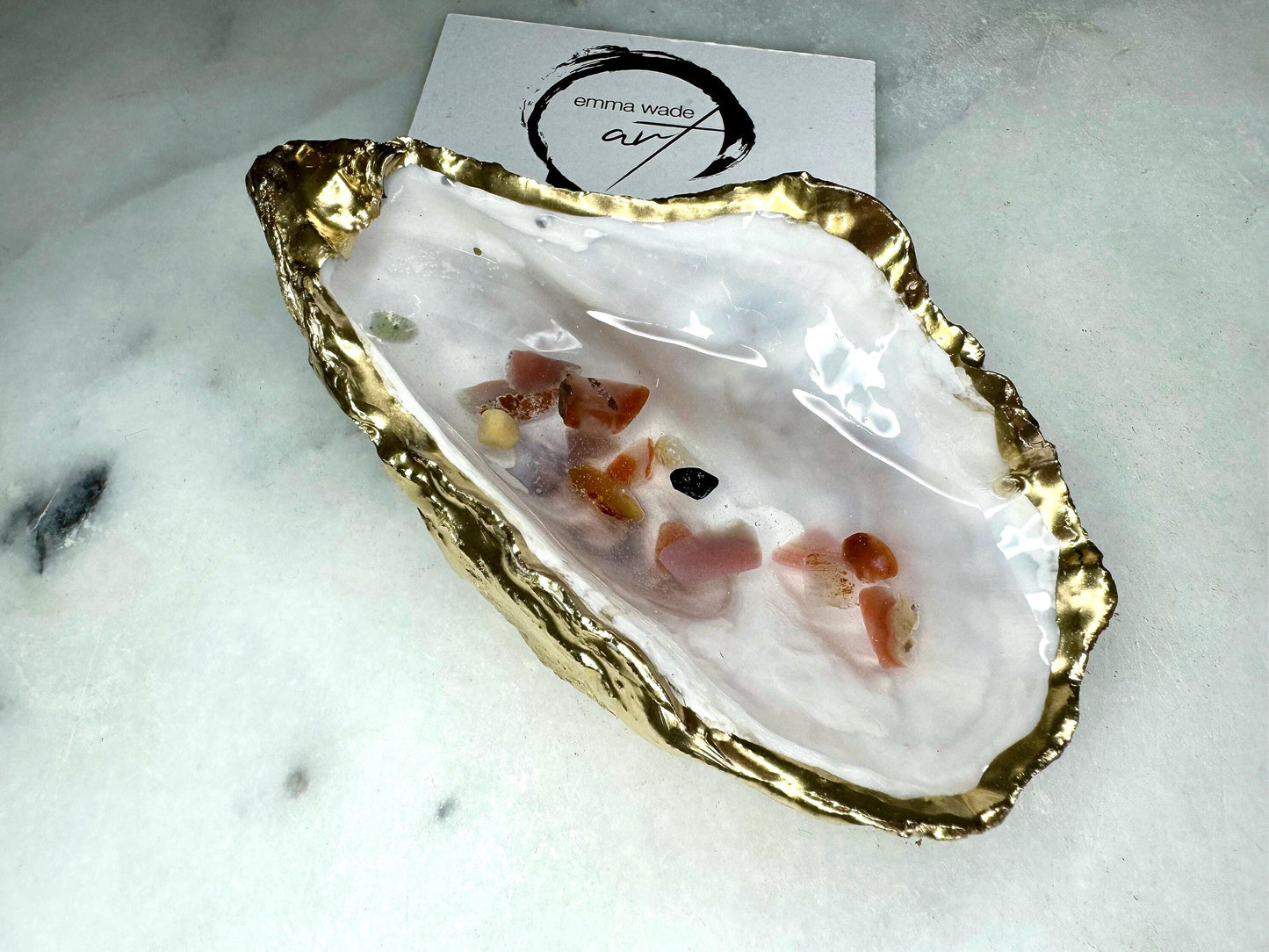 Handmade oyster shell jewellery dish with real Dorset sea glass foraged from the coast and suspended in clear glossy resin to look like a rock pool. Finished with gold leaf trim and a natural pearl interior, this unique shell dish can be used as a ring holder, jewellery tray, or trinket catcher for earrings, cufflinks, or keepsakes. A one-of-a-kind coastal-inspired gift for weddings, anniversaries, birthdays, bridesmaids, Christmas, or Mother’s Day.