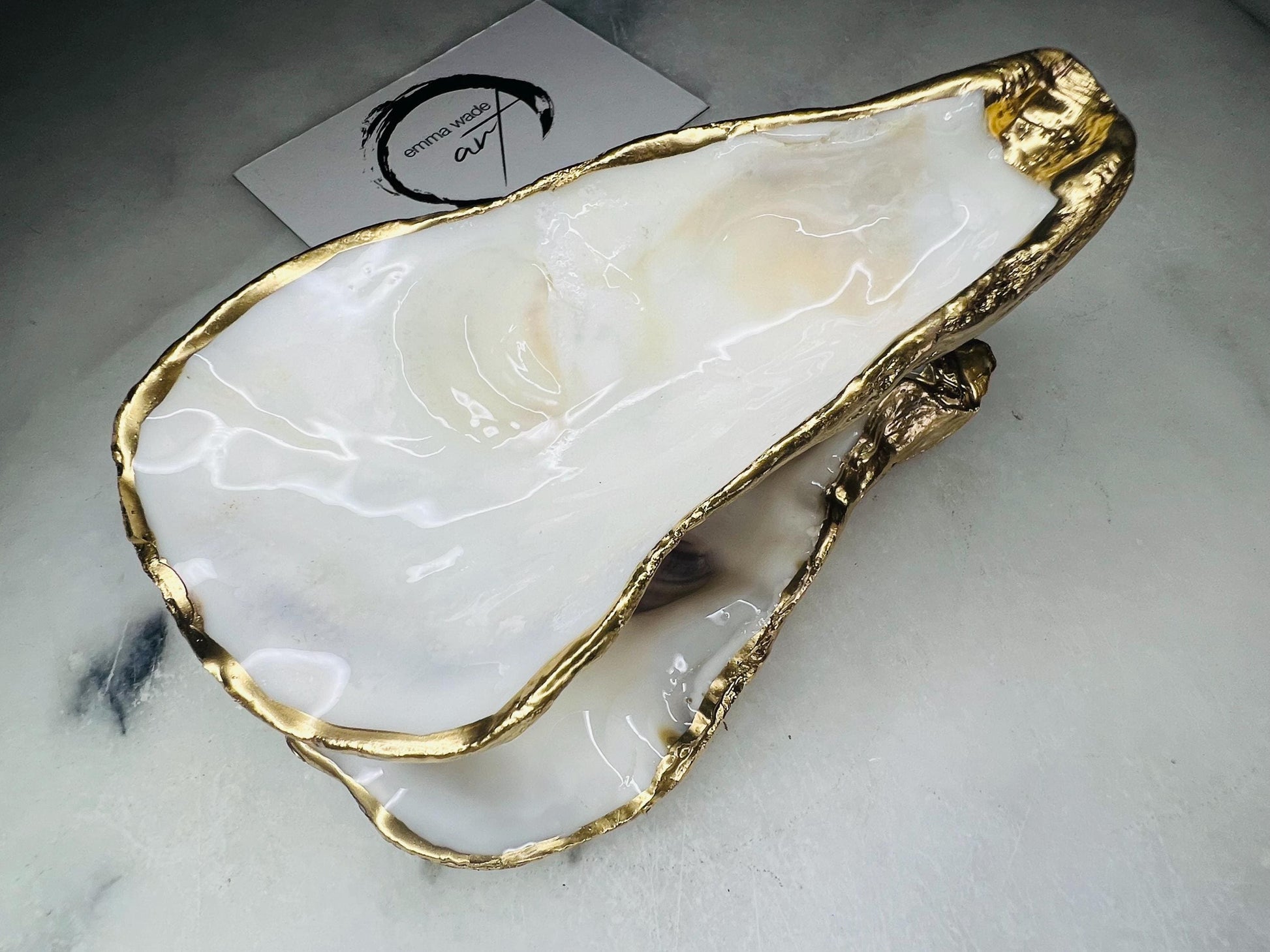 Extra large Dorset oyster shell serving dish set with natural pearl interior and hand-applied gold leaf edging, featuring a cupped XL oyster shell with matching flat shell base. Luxury coastal home décor ideal as a sugar dish, serving bowl, coffee station accessory, or elegant host gift. Handmade using sustainably sourced UK oyster shells and finished with glossy resin and optional gold serving accessories.