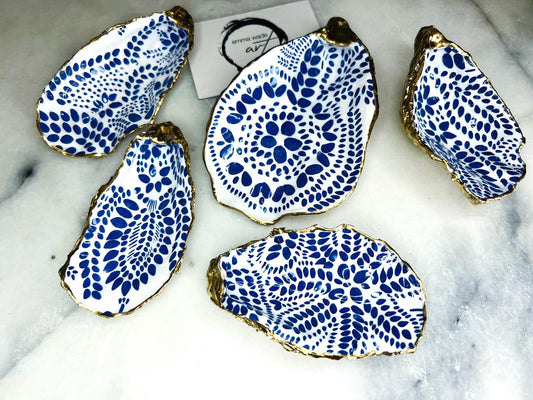 Handmade Dorset oyster shell dish decorated with a Marimekko-inspired Finnish blue floral botanical design. Each shell is hand-finished with liquid gold leaf on the rim and back, then sealed in crystal-clear resin for a glossy, durable finish. A unique oyster shell jewellery holder, ring dish, or trinket tray for earrings, cufflinks, or keepsakes. Perfect as a handmade Scandinavian-inspired gift for weddings, anniversaries, birthdays, or as coastal home décor for Christmas