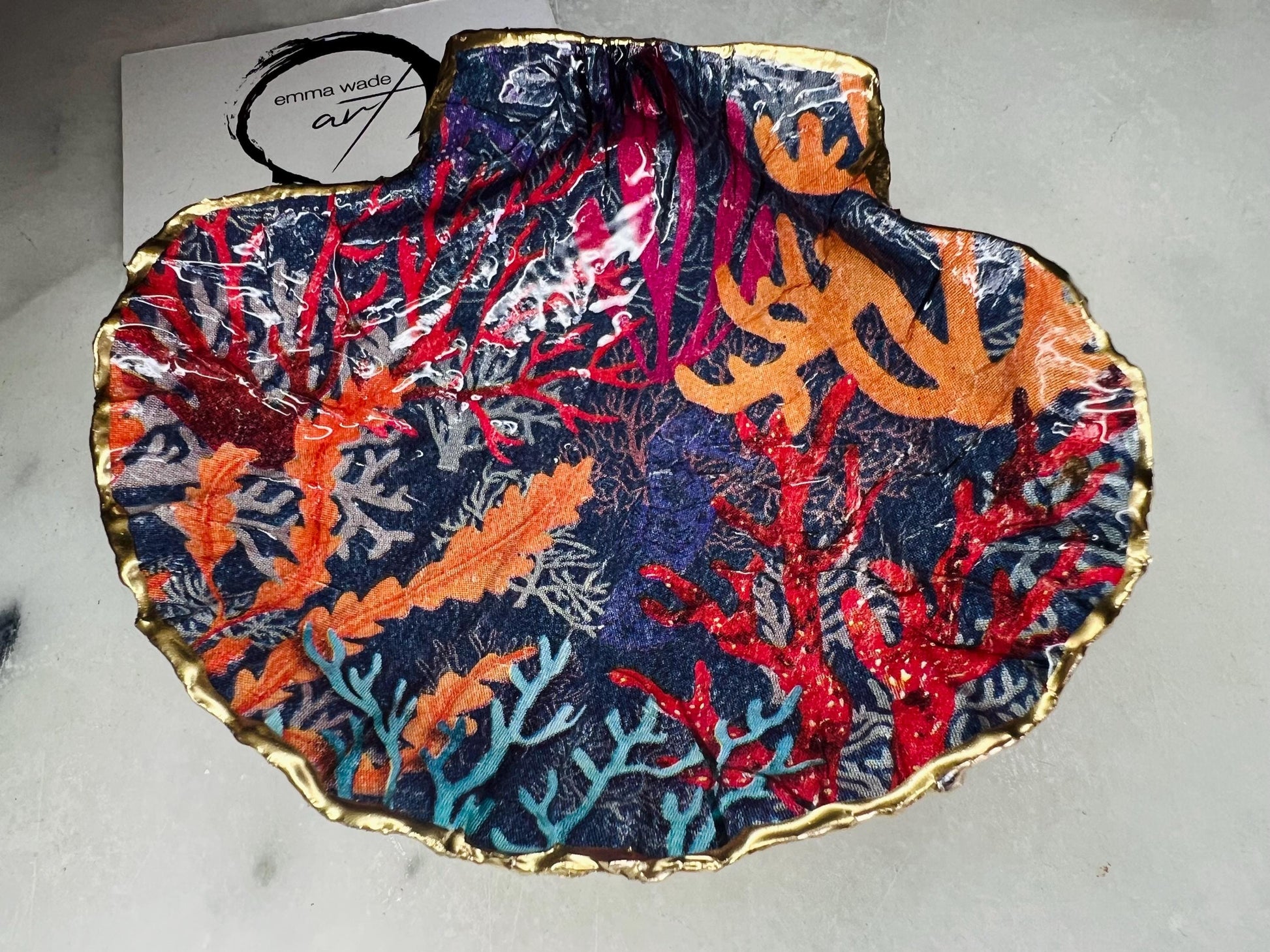 Handmade Dorset scallop shell trinket dish featuring vibrant coral reef and seaweed design in red orange turquoise and navy blue tones, finished with hand gilded gold leaf edging and glossy resin, luxury coastal jewellery holder and ocean inspired decor