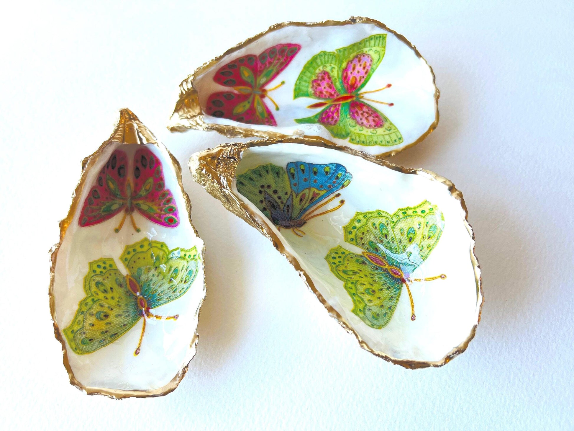 Handmade butterfly oyster shell trinket dish with colourful blue green and pink butterfly designs, edged and backed in gold leaf, Dorset coastal shell jewellery holder with glossy resin finish, luxury ring dish, coastal home decor gift, unique handmade shell dish for jewellery storage, beach house accessory, UK artisan oyster shell dish