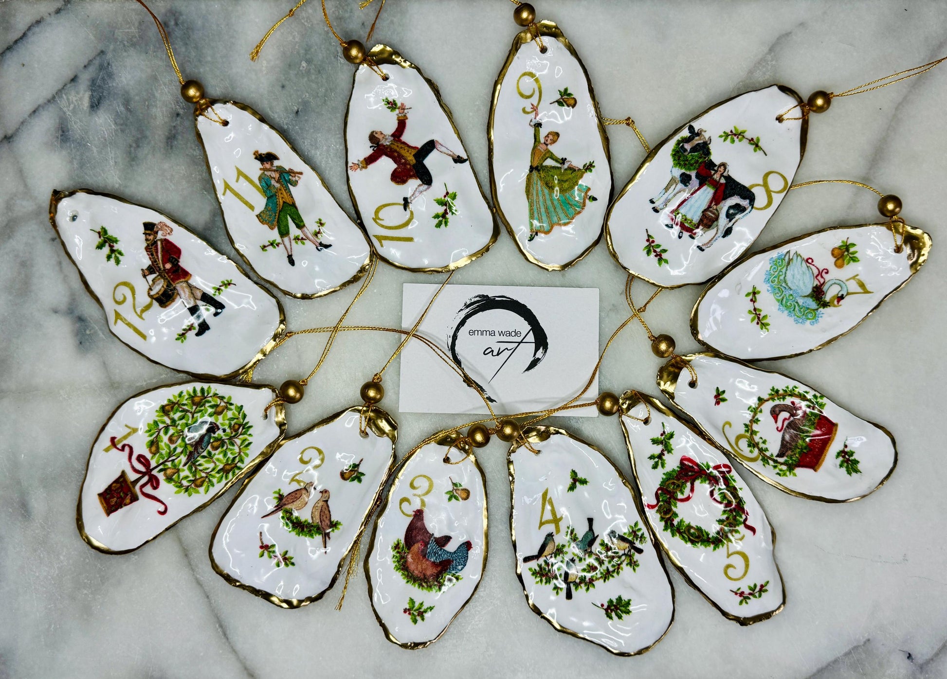Handmade Twelve Days of Christmas oyster shell ornament set featuring all twelve traditional carol illustrations, finished with gold leaf edging, glossy resin and gold hanging cords. Coastal heirloom Christmas decorations handcrafted from Dorset oyster shells.