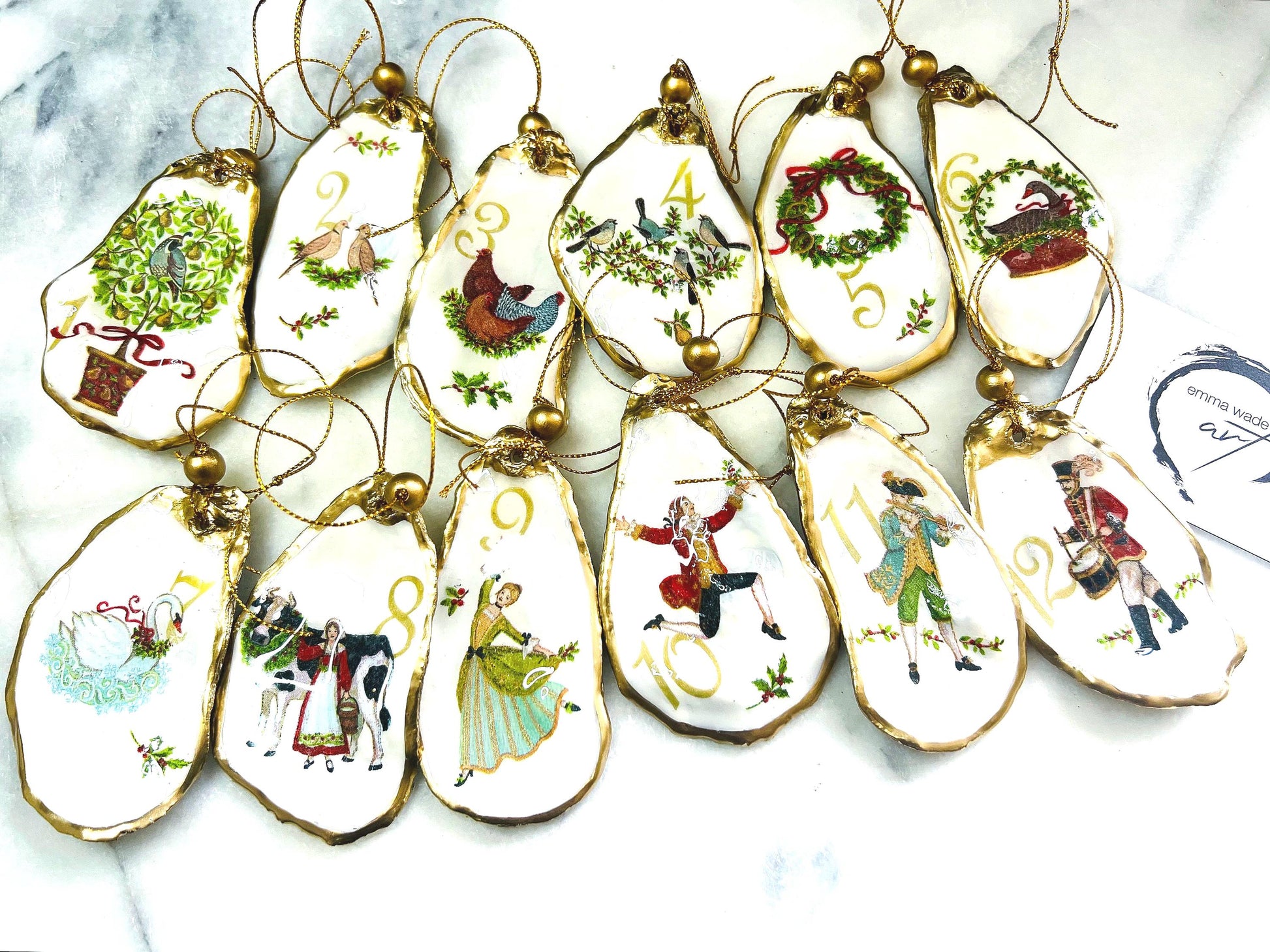 Handmade Twelve Days of Christmas oyster shell ornament set featuring all twelve traditional carol illustrations, finished with gold leaf edging, glossy resin and gold hanging cords. Coastal heirloom Christmas decorations handcrafted from Dorset oyster shells.