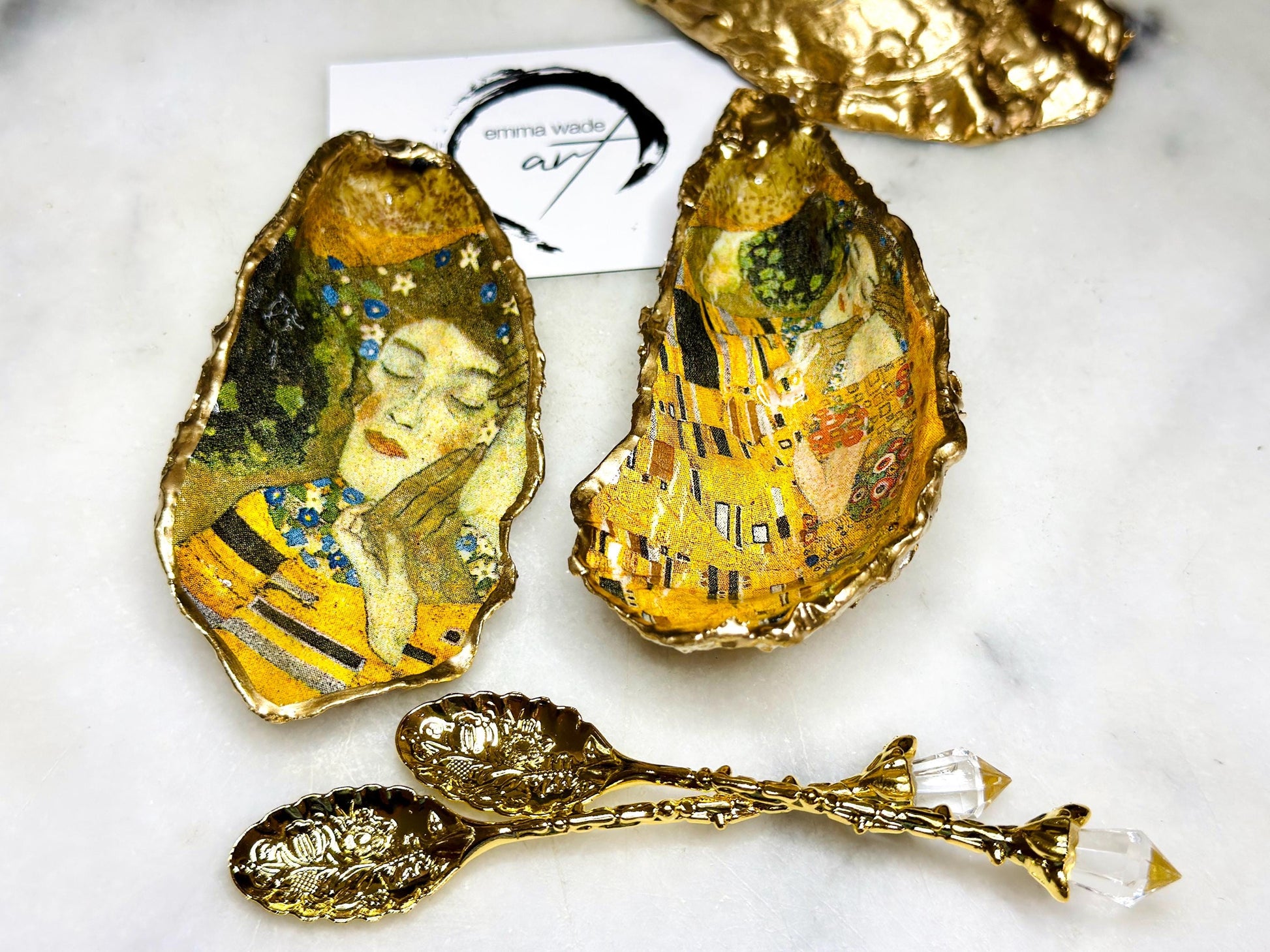 Pair of handmade Dorset oyster shell salt and pepper pinch pots inspired by Gustav Klimt’s The Kiss, decorated with rich gold artwork, hand-finished with liquid gold leaf, and sealed in crystal-hard glossy resin. Luxury coastal serving dishes with optional gold crystal spoons, perfect for weddings, anniversaries, dinner parties, and elegant table décor.
