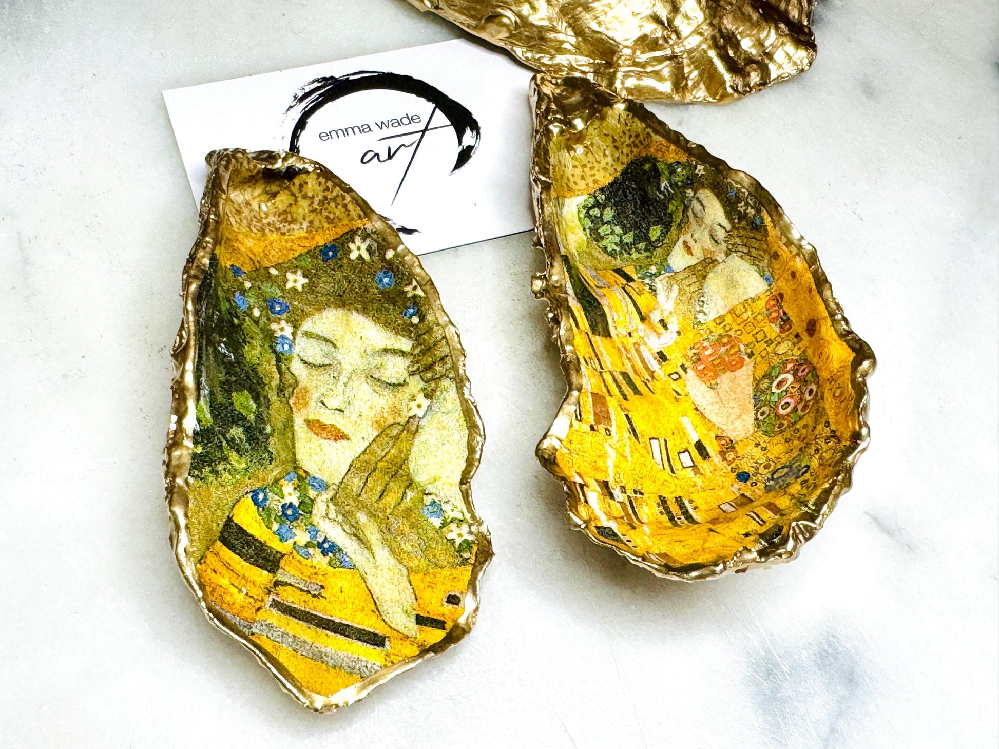 Pair of handmade Dorset oyster shell salt and pepper pinch pots inspired by Gustav Klimt’s The Kiss, decorated with rich gold artwork, hand-finished with liquid gold leaf, and sealed in crystal-hard glossy resin. Luxury coastal serving dishes with optional gold crystal spoons, perfect for weddings, anniversaries, dinner parties, and elegant table décor.