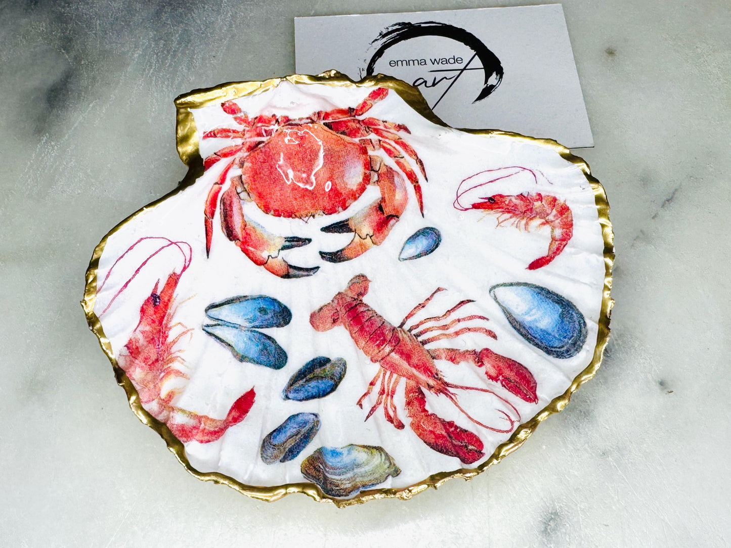 Handmade Dorset scallop shell trinket dish featuring a vibrant red crab and lobster coastal design, hand-gilded with real liquid gold leaf and sealed in crystal-clear glossy resin. Nautical shell jewellery dish inspired by the Dorset coastline, perfect as a ring holder, coastal home décor accent, seaside gift, or luxury beach house accessory.