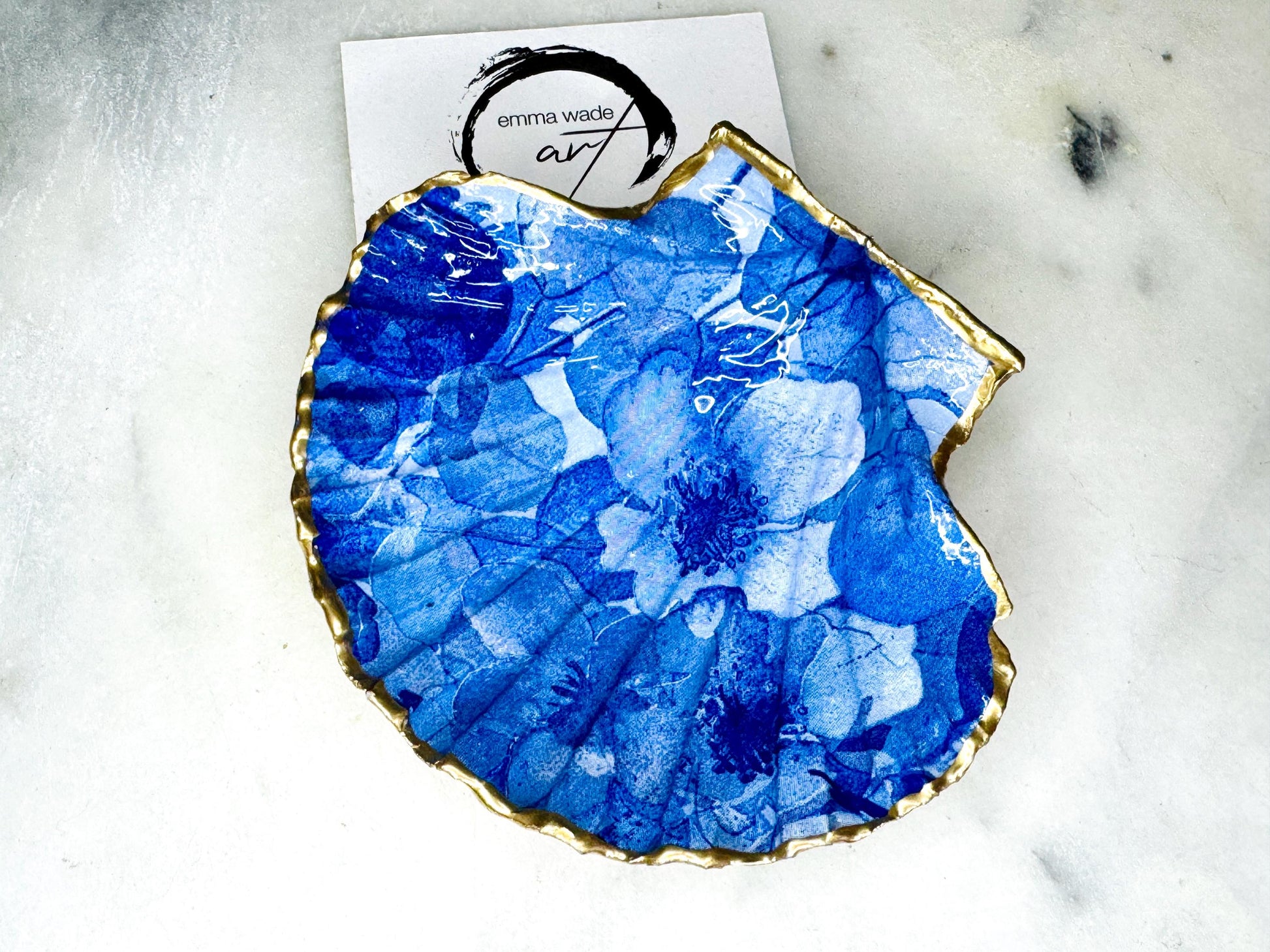 Deep blue watercolour floral scallop shell trinket dish with hand gilded gold leaf edging and glossy resin finish. Handmade Dorset shell jewellery holder in rich cobalt and ocean blue tones, styled as coastal home décor with pearls and gold details.