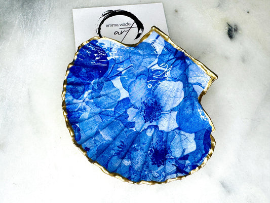 Deep blue watercolour floral scallop shell trinket dish with hand gilded gold leaf edging and glossy resin finish. Handmade Dorset shell jewellery holder in rich cobalt and ocean blue tones, styled as coastal home décor with pearls and gold details.