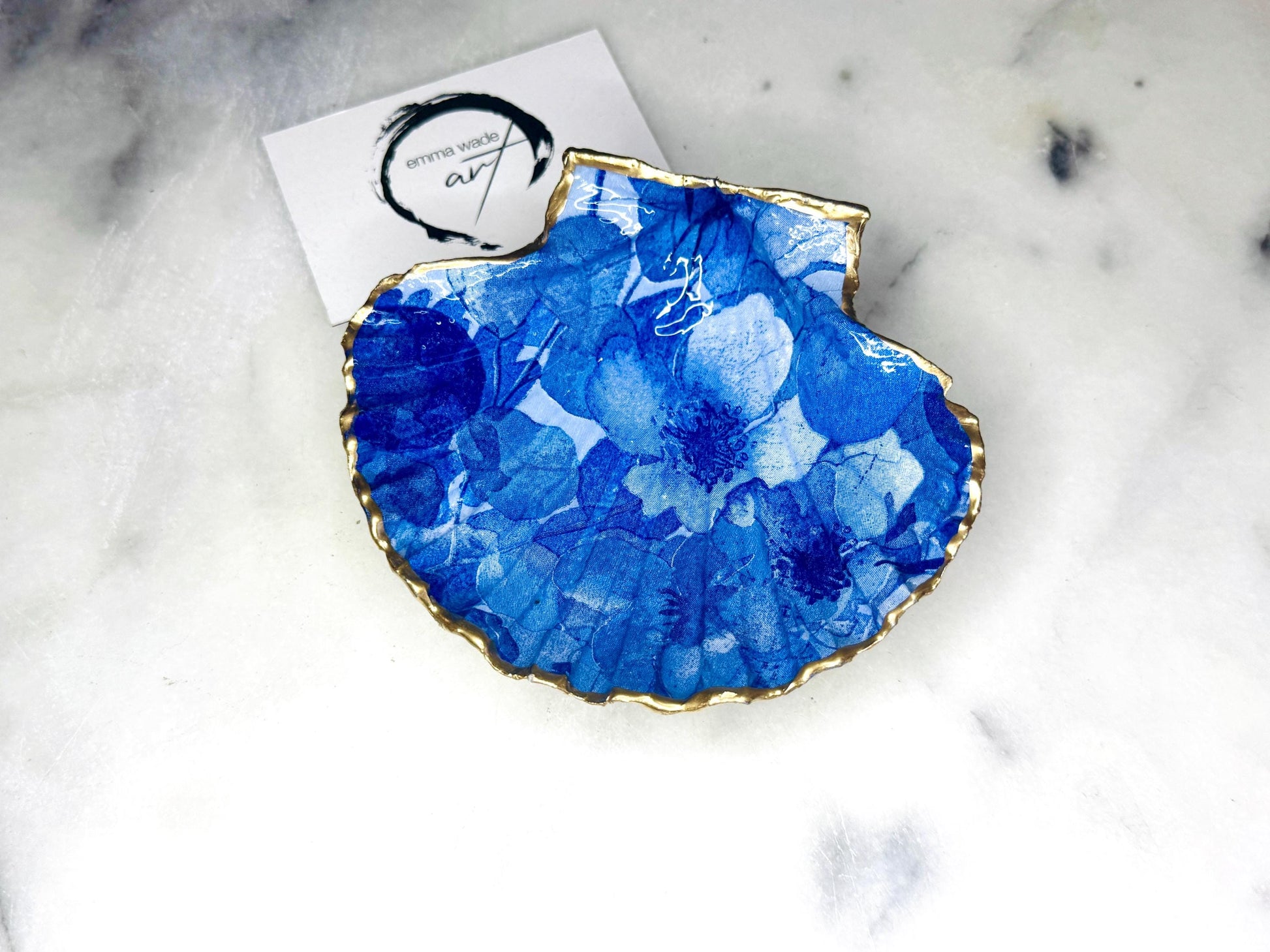 Deep blue watercolour floral scallop shell trinket dish with hand gilded gold leaf edging and glossy resin finish. Handmade Dorset shell jewellery holder in rich cobalt and ocean blue tones, styled as coastal home décor with pearls and gold details.