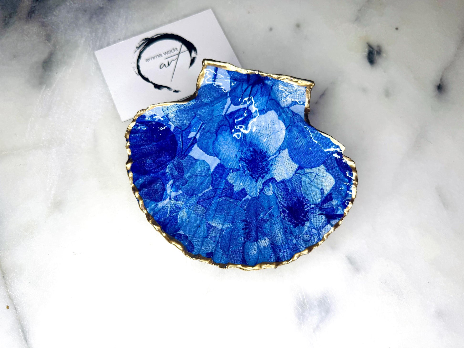 Deep blue watercolour floral scallop shell trinket dish with hand gilded gold leaf edging and glossy resin finish. Handmade Dorset shell jewellery holder in rich cobalt and ocean blue tones, styled as coastal home décor with pearls and gold details.