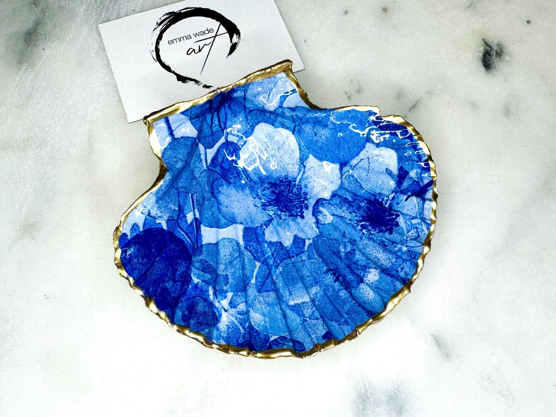 Deep blue watercolour floral scallop shell trinket dish with hand gilded gold leaf edging and glossy resin finish. Handmade Dorset shell jewellery holder in rich cobalt and ocean blue tones, styled as coastal home décor with pearls and gold details.