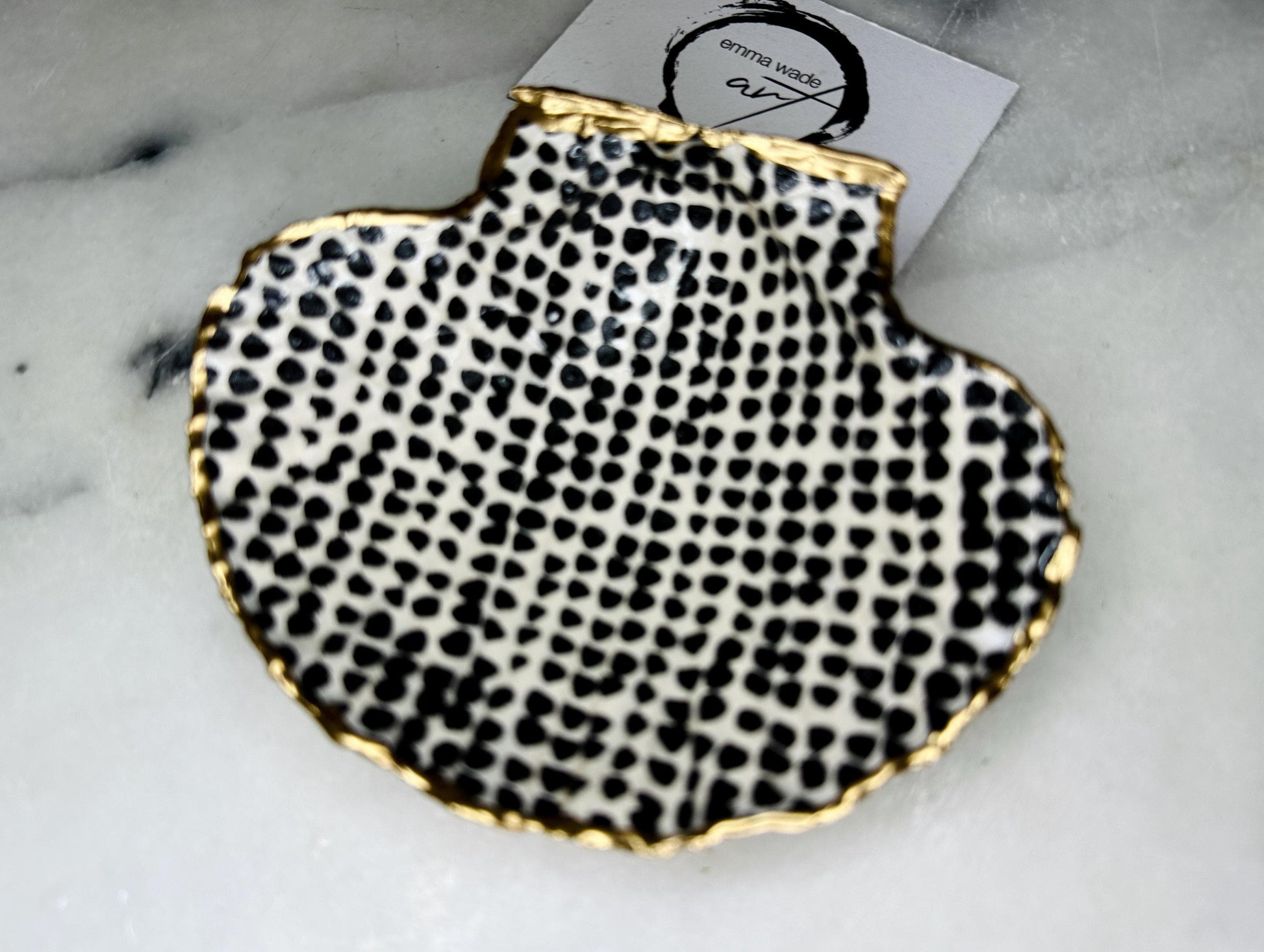 Handcrafted black and white dotted Dorset scallop shell trinket dish, gilded with real gold leaf and sealed in crystal-clear resin. Perfect as a jewellery holder, cufflink tray, tea light holder, or coastal home accent. Each eco-friendly shell is ethically sourced from the Dorset coastline, individually hand finished in Surrey, and presented in a sustainable gift box. A thoughtful handmade gift for ocean lovers, weddings, birthdays, or coastal home décor.