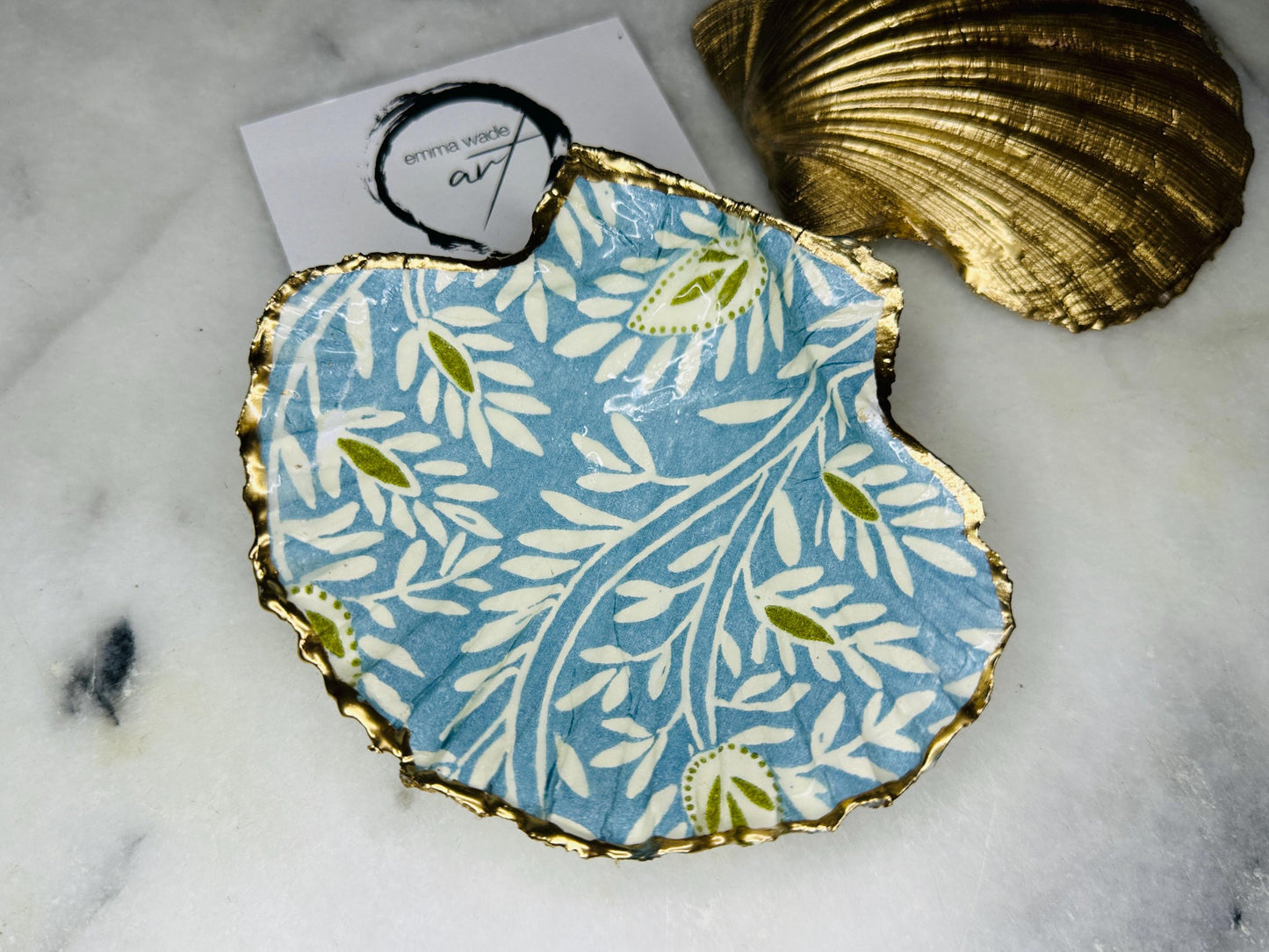 Elegant Blue Green floral scallop shell trinket dish, hand-painted and gilded with liquid gold leaf before being sealed in crystal-clear resin. Each shell is a one-of-a-kind Dorset creation, perfect as a jewellery holder, tea light dish, or coastal home décor accent. A beautiful handmade ocean-inspired gift, presented in eco-friendly packaging and finished with sustainable care and artistry