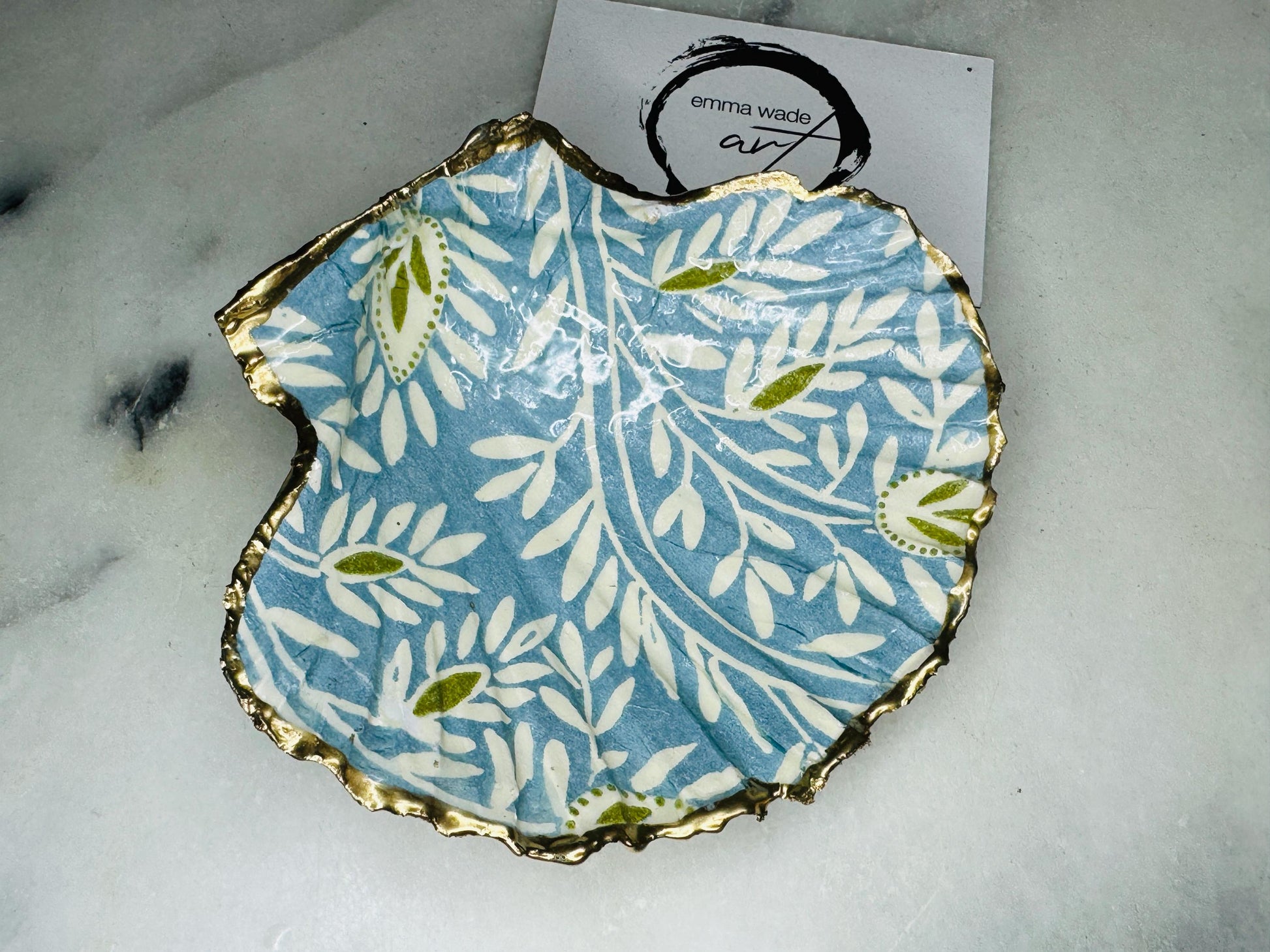 Handcrafted Blue and Green floral scallop shell trinket dish, gilded with liquid gold leaf and sealed in resin. Inspired by the Dorset coastline, this unique jewellery holder or trinket bowl is made from an authentic scallop shell and presented in a sustainable gift box. A thoughtful handmade coastal décor piece and ocean lover gift, ideal for weddings, birthdays, or elegant home styling.