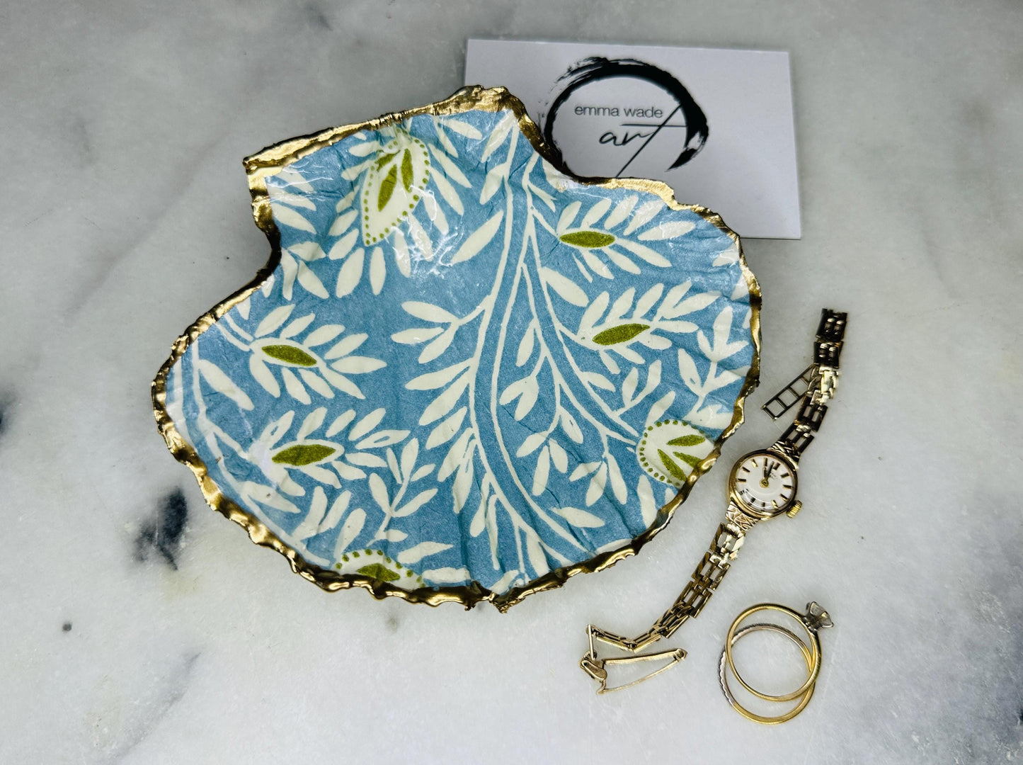 Elegant Blue Green floral scallop shell trinket dish, hand-painted and gilded with liquid gold leaf before being sealed in crystal-clear resin. Each shell is a one-of-a-kind Dorset creation, perfect as a jewellery holder, tea light dish, or coastal home décor accent. A beautiful handmade ocean-inspired gift, presented in eco-friendly packaging and finished with sustainable care and artistry