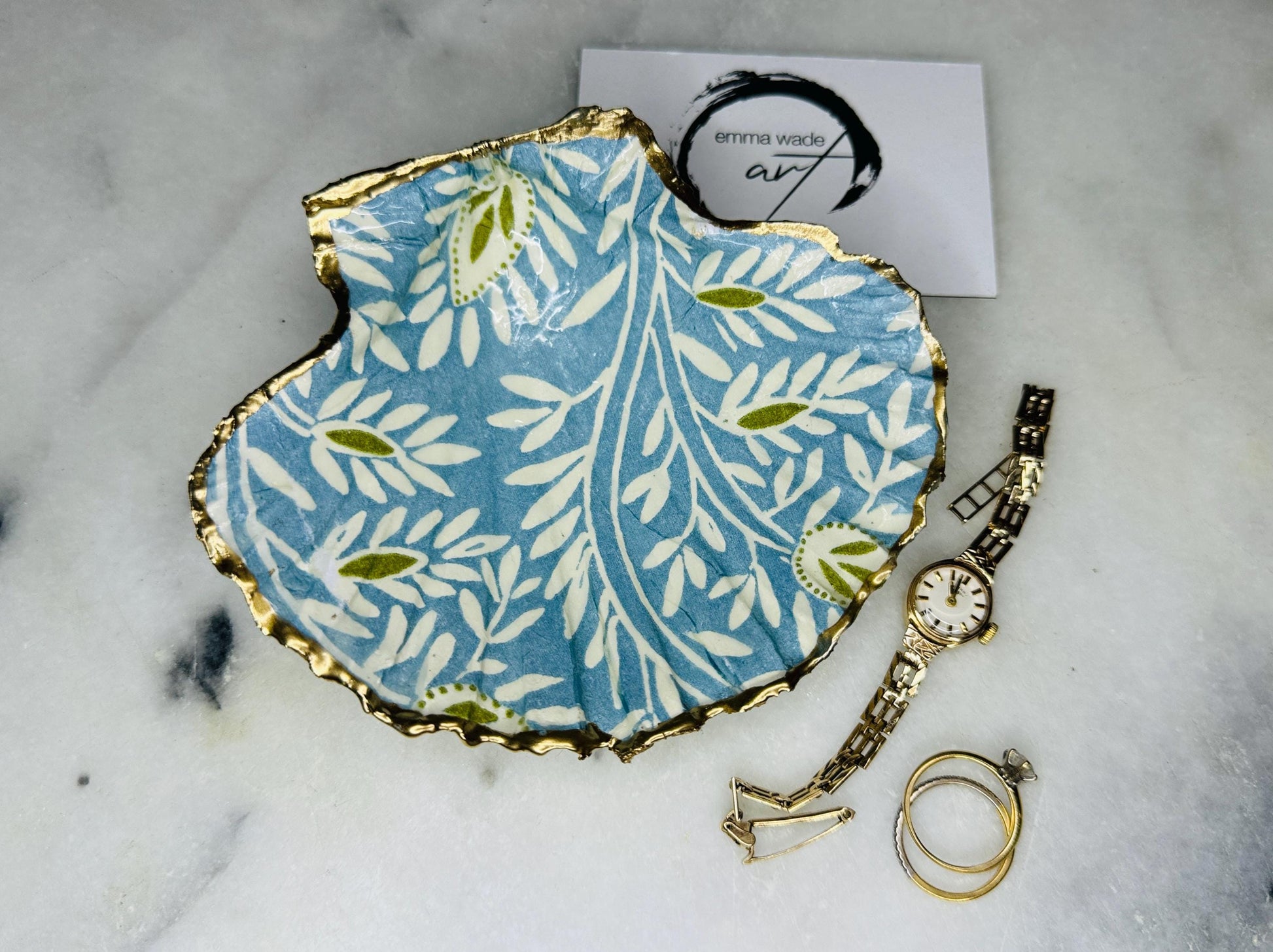 Elegant Blue Green floral scallop shell trinket dish, hand-painted and gilded with liquid gold leaf before being sealed in crystal-clear resin. Each shell is a one-of-a-kind Dorset creation, perfect as a jewellery holder, tea light dish, or coastal home décor accent. A beautiful handmade ocean-inspired gift, presented in eco-friendly packaging and finished with sustainable care and artistry