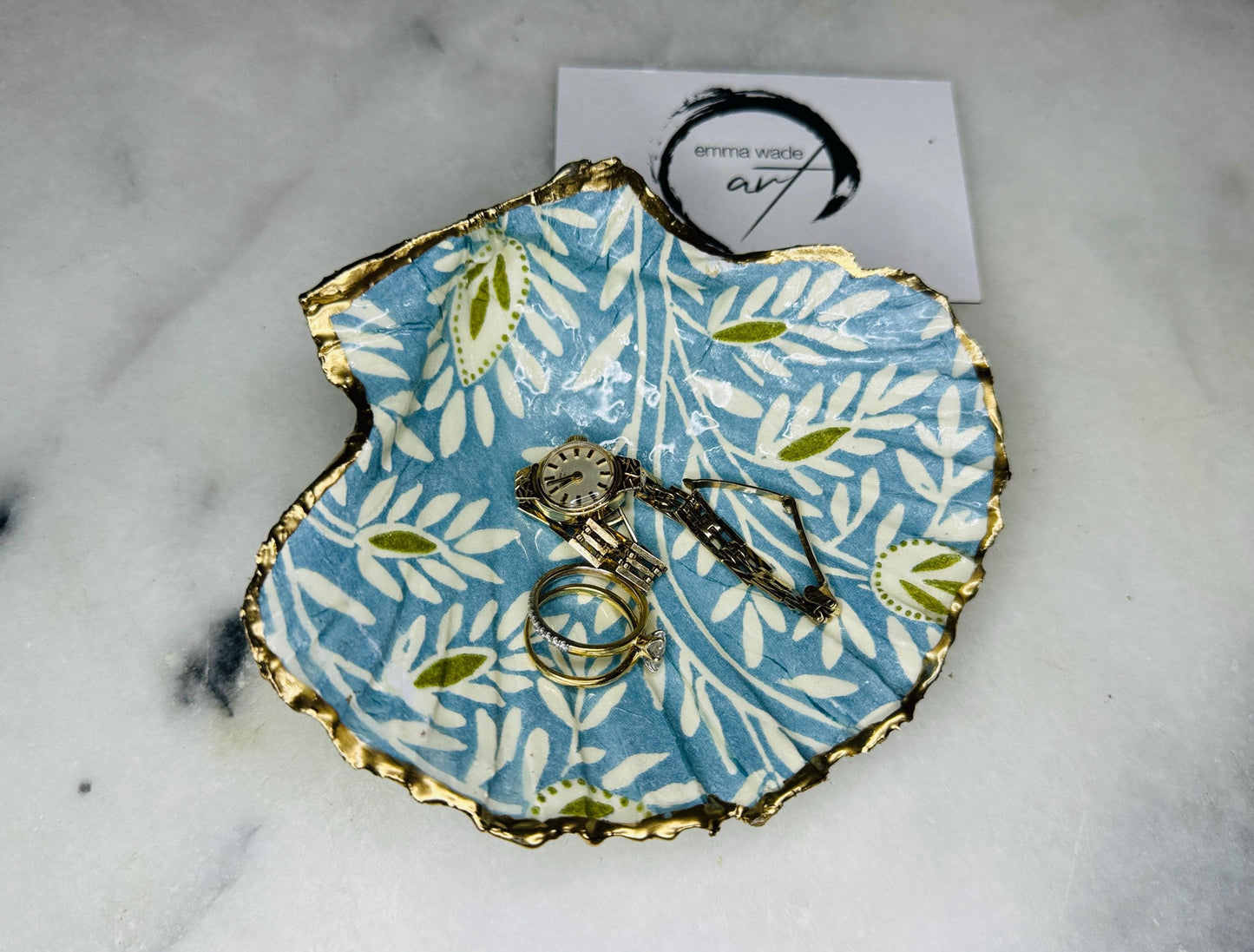 Handcrafted Blue and Green floral scallop shell trinket dish, gilded with liquid gold leaf and sealed in resin. Inspired by the Dorset coastline, this unique jewellery holder or trinket bowl is made from an authentic scallop shell and presented in a sustainable gift box. A thoughtful handmade coastal décor piece and ocean lover gift, ideal for weddings, birthdays, or elegant home styling.