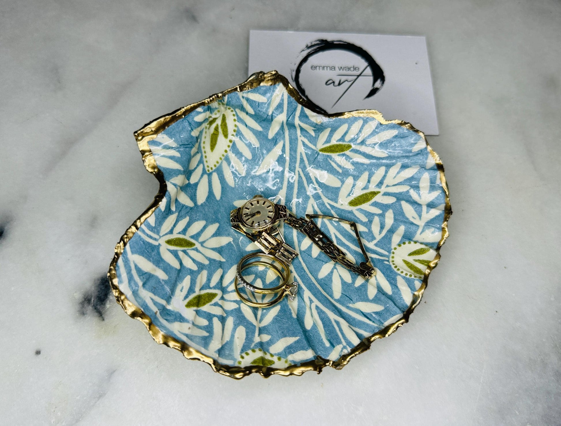 Handcrafted Blue and Green floral scallop shell trinket dish, gilded with liquid gold leaf and sealed in resin. Inspired by the Dorset coastline, this unique jewellery holder or trinket bowl is made from an authentic scallop shell and presented in a sustainable gift box. A thoughtful handmade coastal décor piece and ocean lover gift, ideal for weddings, birthdays, or elegant home styling.