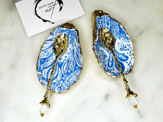 Blue and white paisley oyster shell salt cellar set with gold leaf edging and matching gold crystal spoons. Handmade Dorset oyster shell pinch pots finished in glossy food safe resin. Coastal dining decor and luxury beach house table accessory.