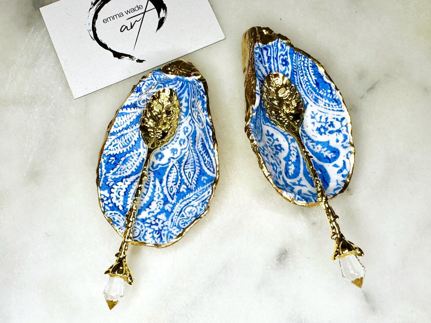 Blue and white paisley oyster shell salt cellar set with gold leaf edging and matching gold crystal spoons. Handmade Dorset oyster shell pinch pots finished in glossy food safe resin. Coastal dining decor and luxury beach house table accessory.