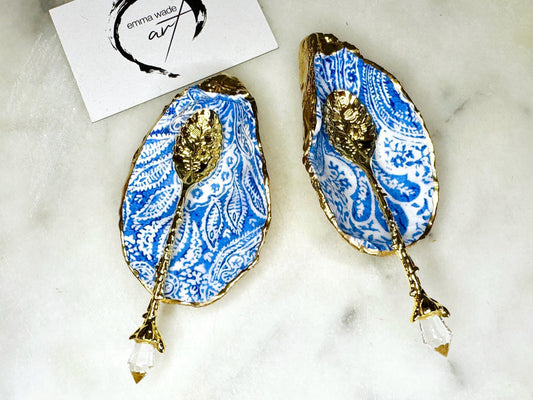 Blue and white paisley oyster shell salt cellar set with gold leaf edging and matching gold crystal spoons. Handmade Dorset oyster shell pinch pots finished in glossy food safe resin. Coastal dining decor and luxury beach house table accessory.