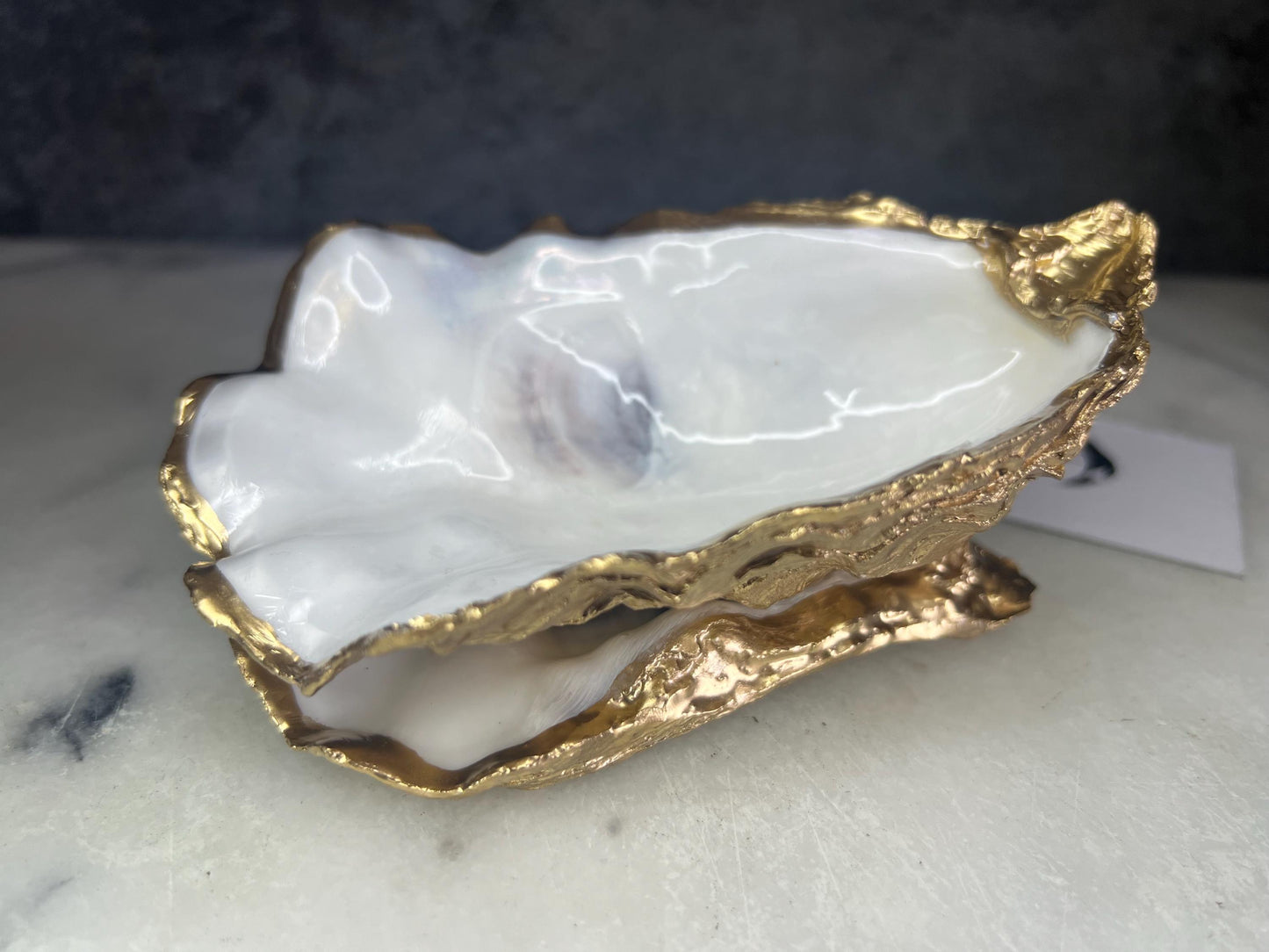 Extra large Dorset oyster shell serving dish set with natural pearl interior and hand-applied gold leaf edging, featuring a cupped XL oyster shell with matching flat shell base. Luxury coastal home décor ideal as a sugar dish, serving bowl, coffee station accessory, or elegant host gift. Handmade using sustainably sourced UK oyster shells and finished with glossy resin and optional gold serving accessories.