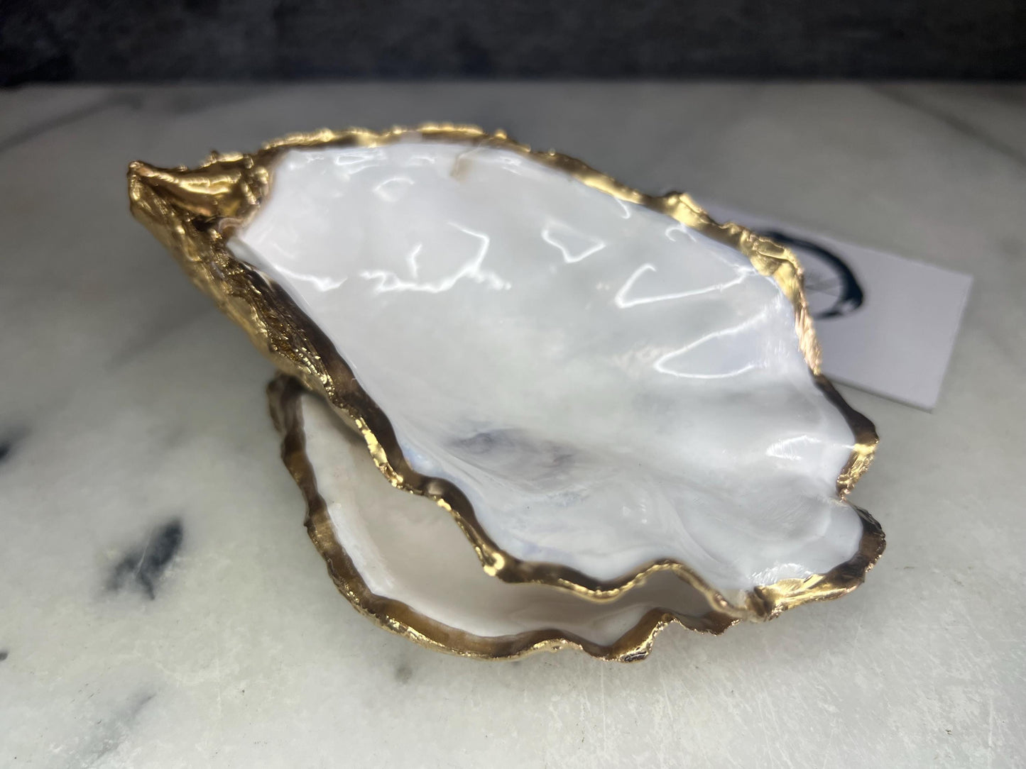 Extra large Dorset oyster shell serving dish set with natural pearl interior and hand-applied gold leaf edging, featuring a cupped XL oyster shell with matching flat shell base. Luxury coastal home décor ideal as a sugar dish, serving bowl, coffee station accessory, or elegant host gift. Handmade using sustainably sourced UK oyster shells and finished with glossy resin and optional gold serving accessories.