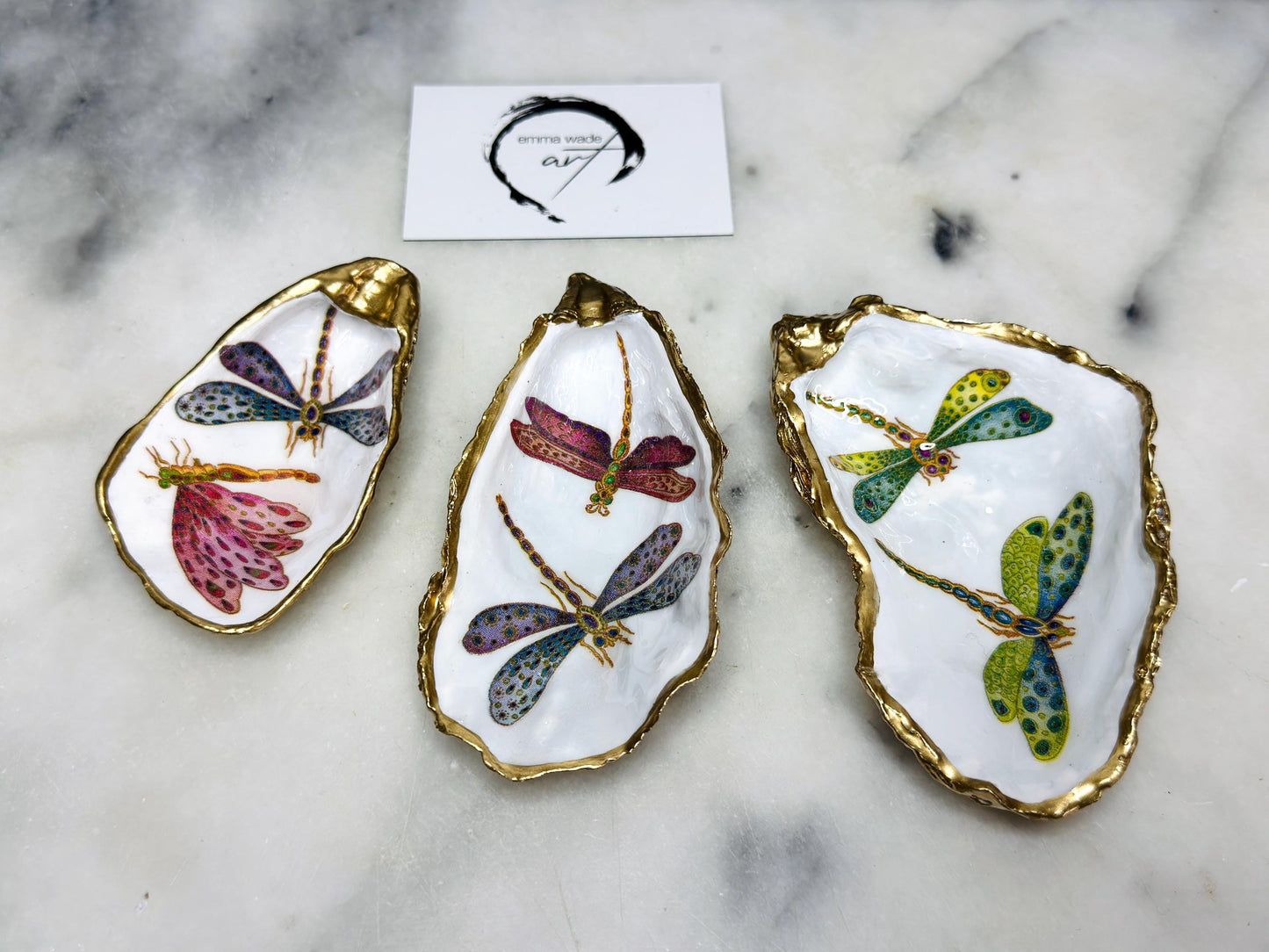Handmade dragonfly oyster shell trinket dish with hand-gilded gold leaf edges and glossy resin finish, created from sustainably sourced Dorset shells. Unique coastal jewellery holder and ring dish, ideal as a vanity tray, trinket tray or decorative keepsake. Nature inspired home decor gift for birthdays, weddings, anniversaries, housewarmings and Mother’s Day. One of a kind artisan shell dish, beautifully presented in a gift box.