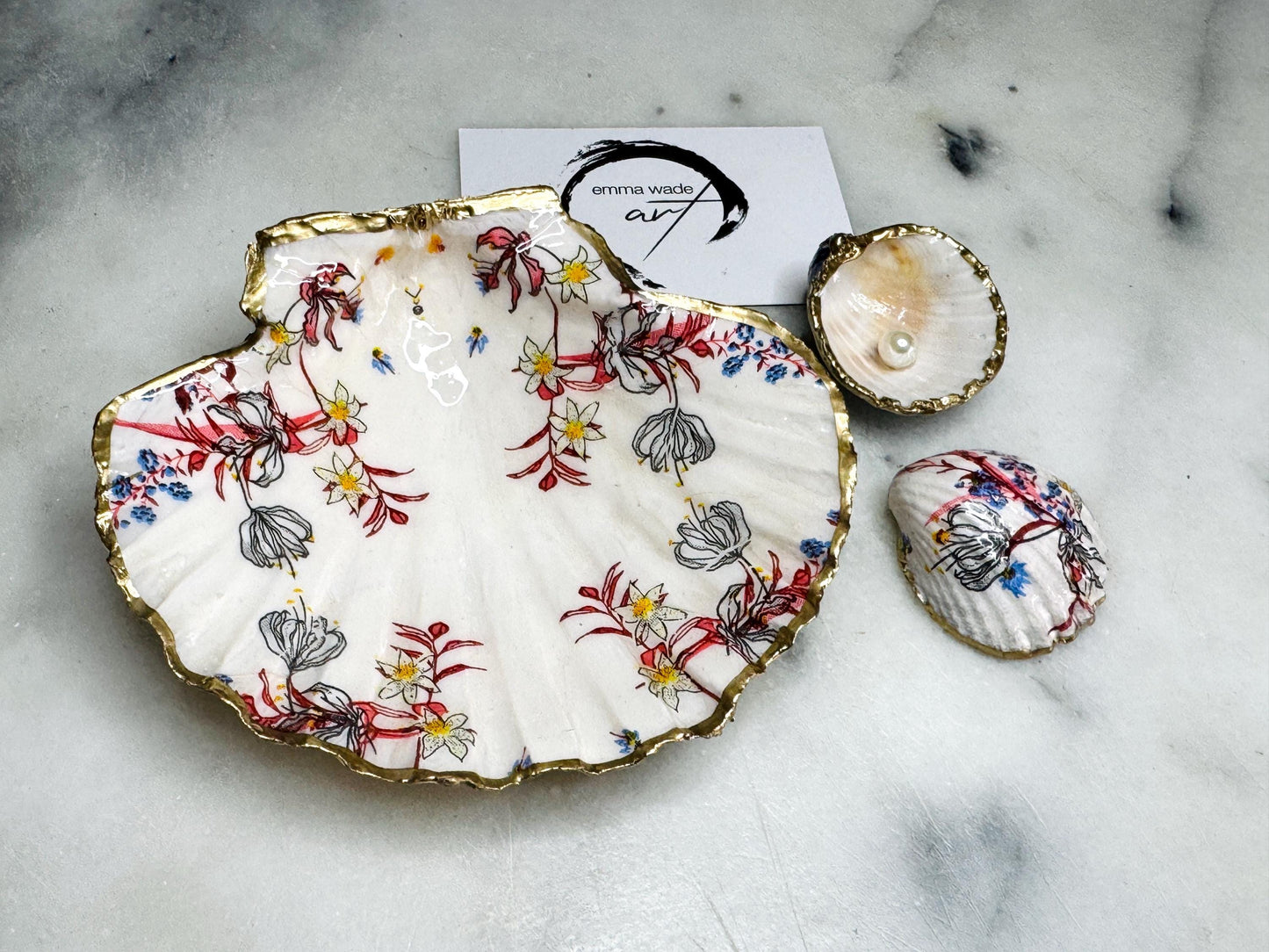 Handcrafted Dorset shell dish set featuring red and blue floral designs on scallop and cockle shells | Cockle shell includes a Swarovski pearl ring rest to prevent rings from sliding | Gilded with liquid gold leaf and sealed with glossy resin | Perfect as a jewellery or ring holder, trinket tray, or coastal gift | Each shell is sustainably sourced and hand finished in the UK | Ideal wedding or anniversary keepsake
