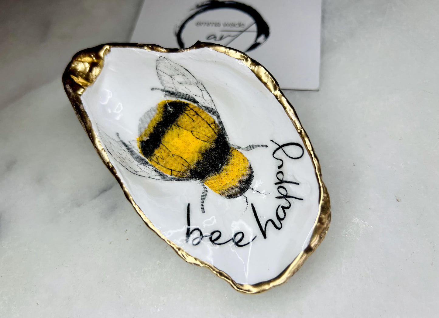 bee happy oyster shell trinket dish, Dorset oyster shell jewellery holder, handmade bee design coastal decor, gold leaf gilded oyster shell ornament, sustainable oyster shell dish UK, bumble bee oyster shell jewellery tray, nature inspired bee oyster shell gift, eco friendly oyster shell bathroom accessory, oyster shell salt and pepper pinch pot, unique bee themed oyster shell keepsake, handmade Dorset oyster shell decor, bee lover jewellery dish gift, coastal oyster shell art UK